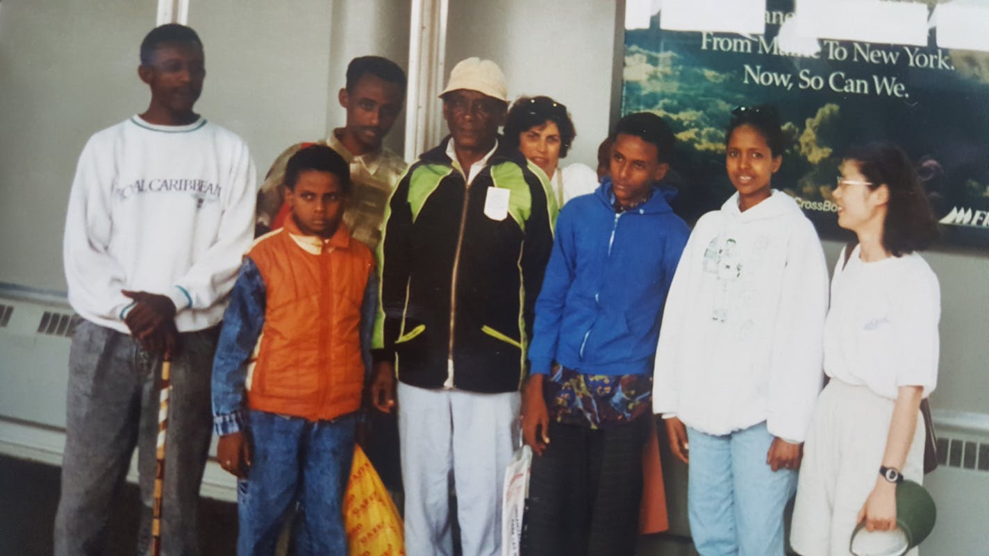 Ali Abdalla, in an orange vest, with his parents, siblings and resettlement sponsors on the day in 1996 he arrived in New York City. The photo was provided by the family.