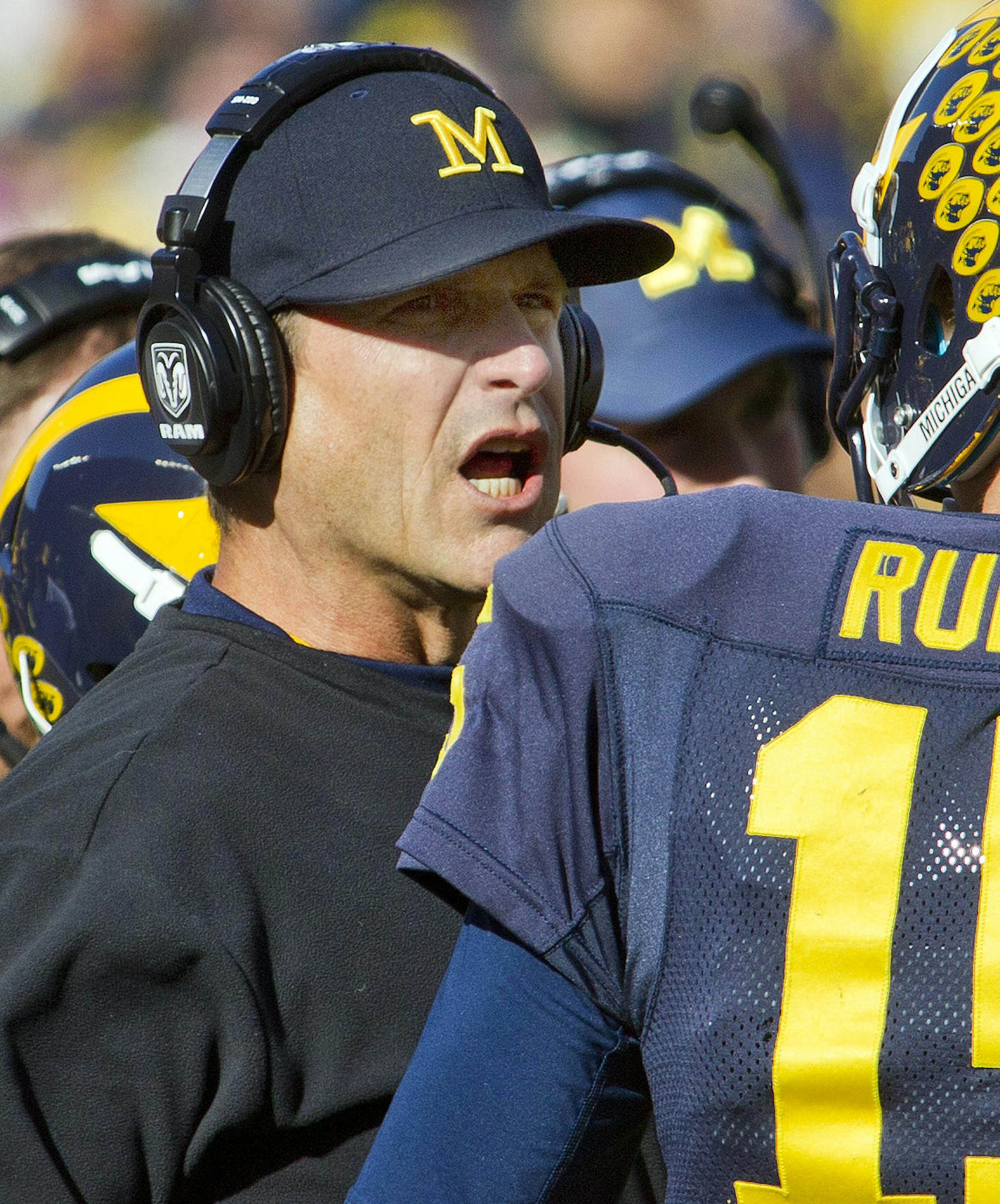Michigan head coach Jim Harbaugh, left, gives advice to quarterback Jake Rudock (15) during a timeout in the first quarter of an NCAA college football game against Northwestern in Ann Arbor, Mich., Saturday, Oct. 10, 2015. (AP Photo/Tony Ding)