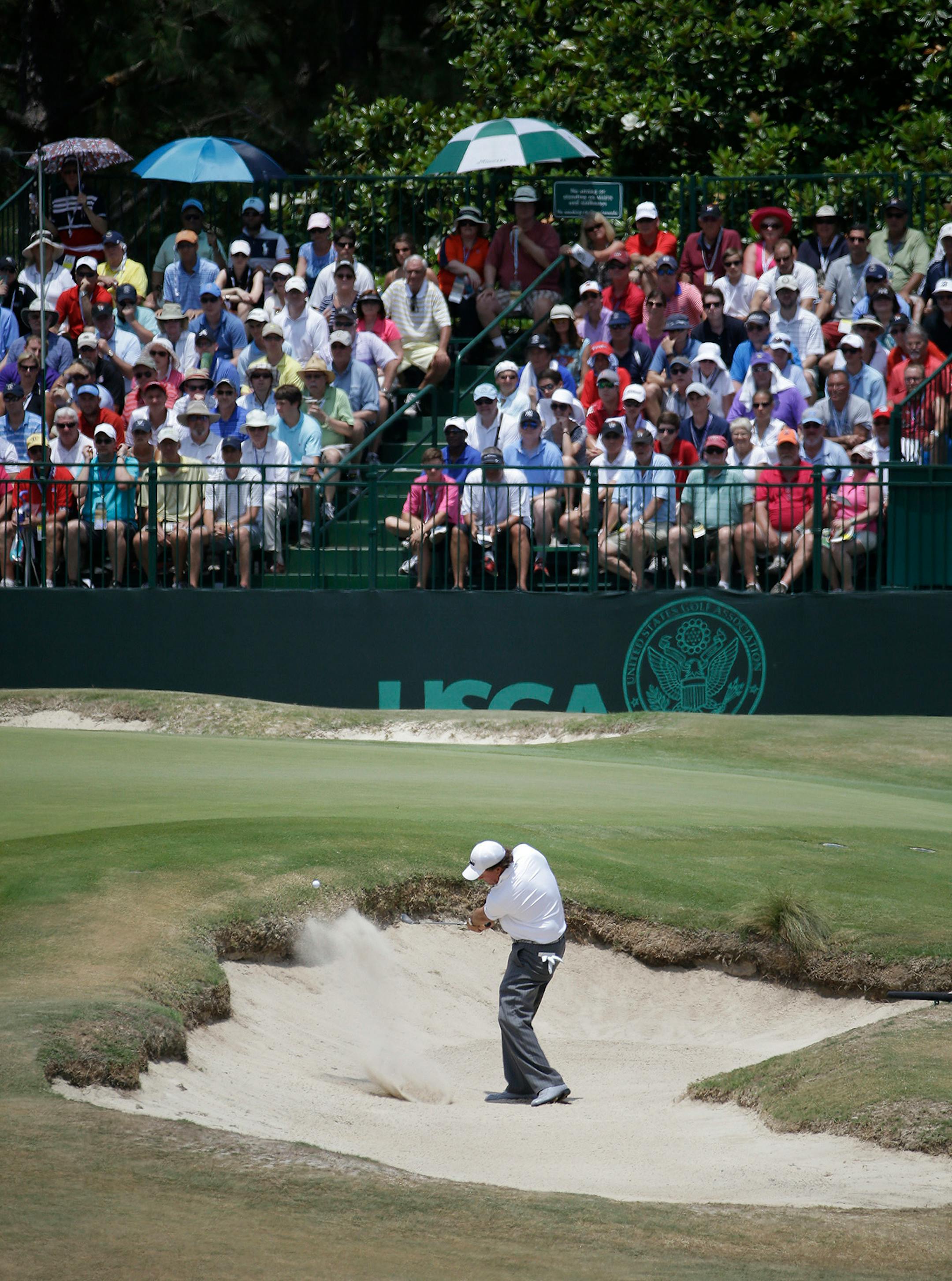 Phil Mickelson hits out of the bunker on the ninth hole during the third round of the U.S. Open golf tournament in Pinehurst, N.C., Saturday, June 14, 2014.