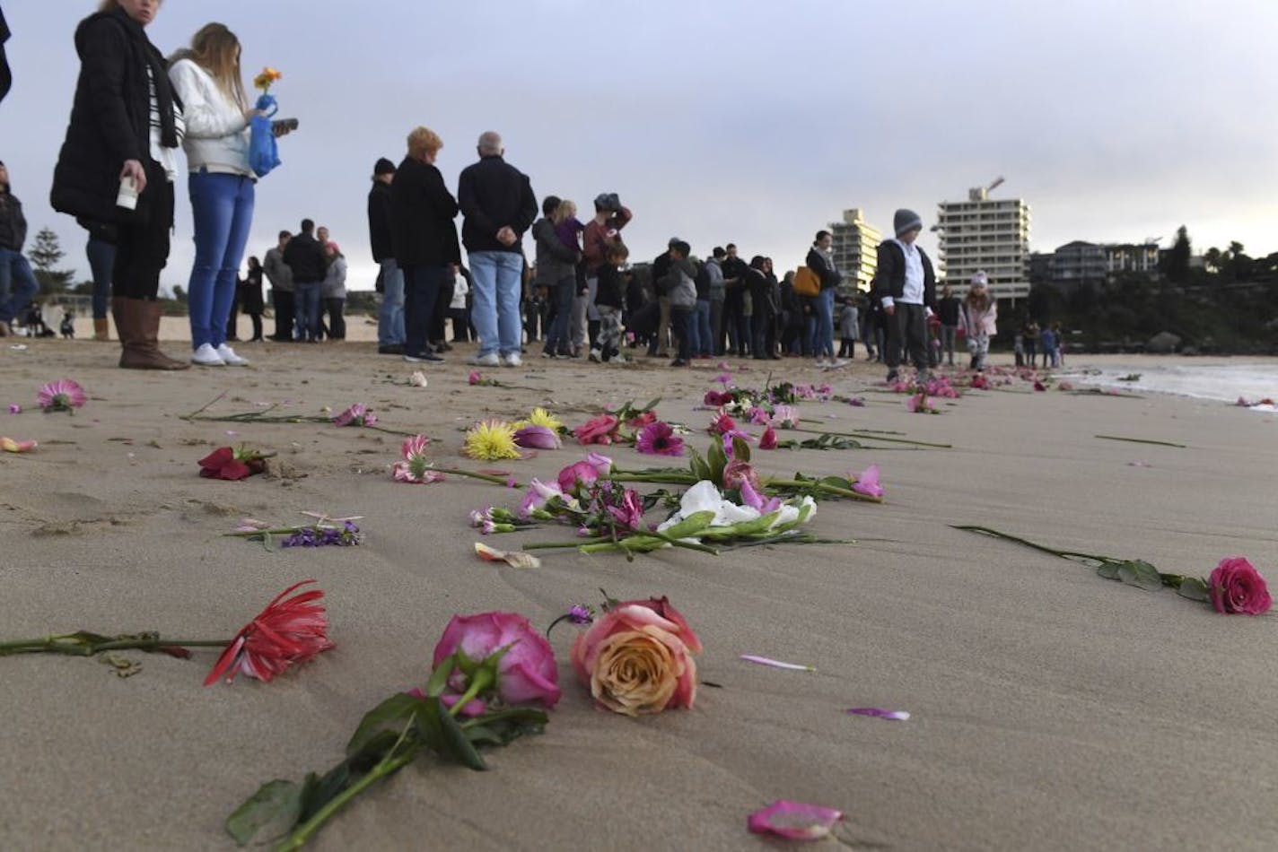 Family and friends gather on Sydney's Freshwater Beach, Wednesday, July 19, 2017, following a candlelight vigil, where they threw hundreds of pink flowers into the ocean for Justine Damond who was shot by a Minneapolis last weekend. Damond, a 40-year-old spiritual healer and bride-to-be, was shot Saturday night by one of the two officers responding to her 911 call. Damond had called police about what she thought was a sexual assault in the alley behind her home.