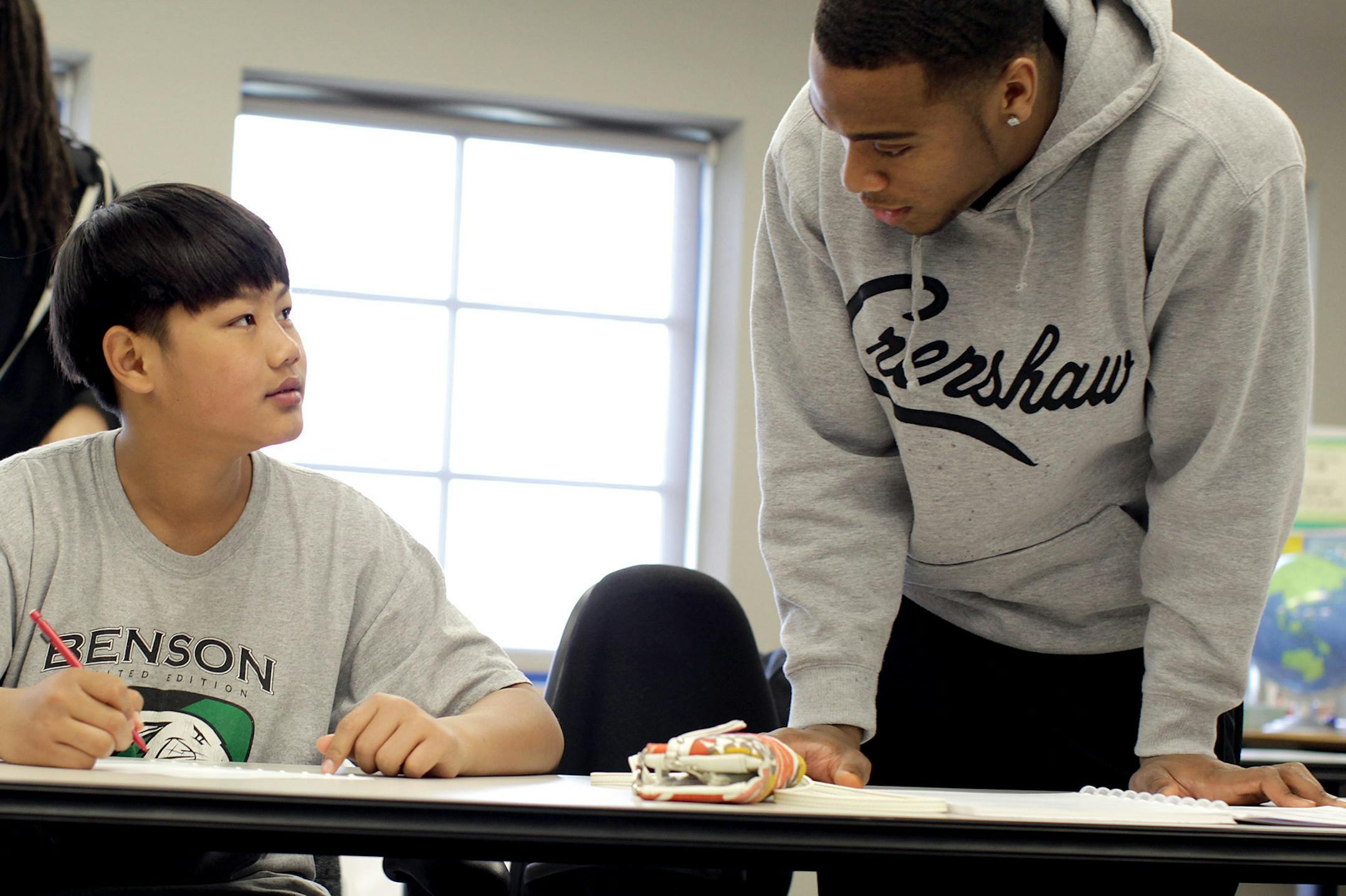 Gopher football player Cedric Thompson, right, asks Eh Hay Tha Taw, 13, if he needs help with homework as Thompson and teammate Derrick Wells, far left, volunteer with the Wells Academy at Fred Wells Tennis and Education Center in St. Paul May 5, 2013. Thompson was the first in his family to graduate from high school, and he has a strong desire to help others do the same and continue on to college. (Courtney Perry/Special to the Star Tribune)