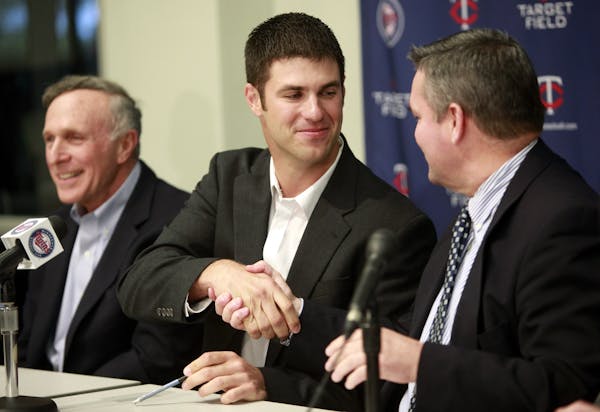 Minnesota Twins catcher Joe Mauer, center, shakes hands with Twins general manager Bill Smith, right, after signing a contract as Mauer's agent Ron Sh