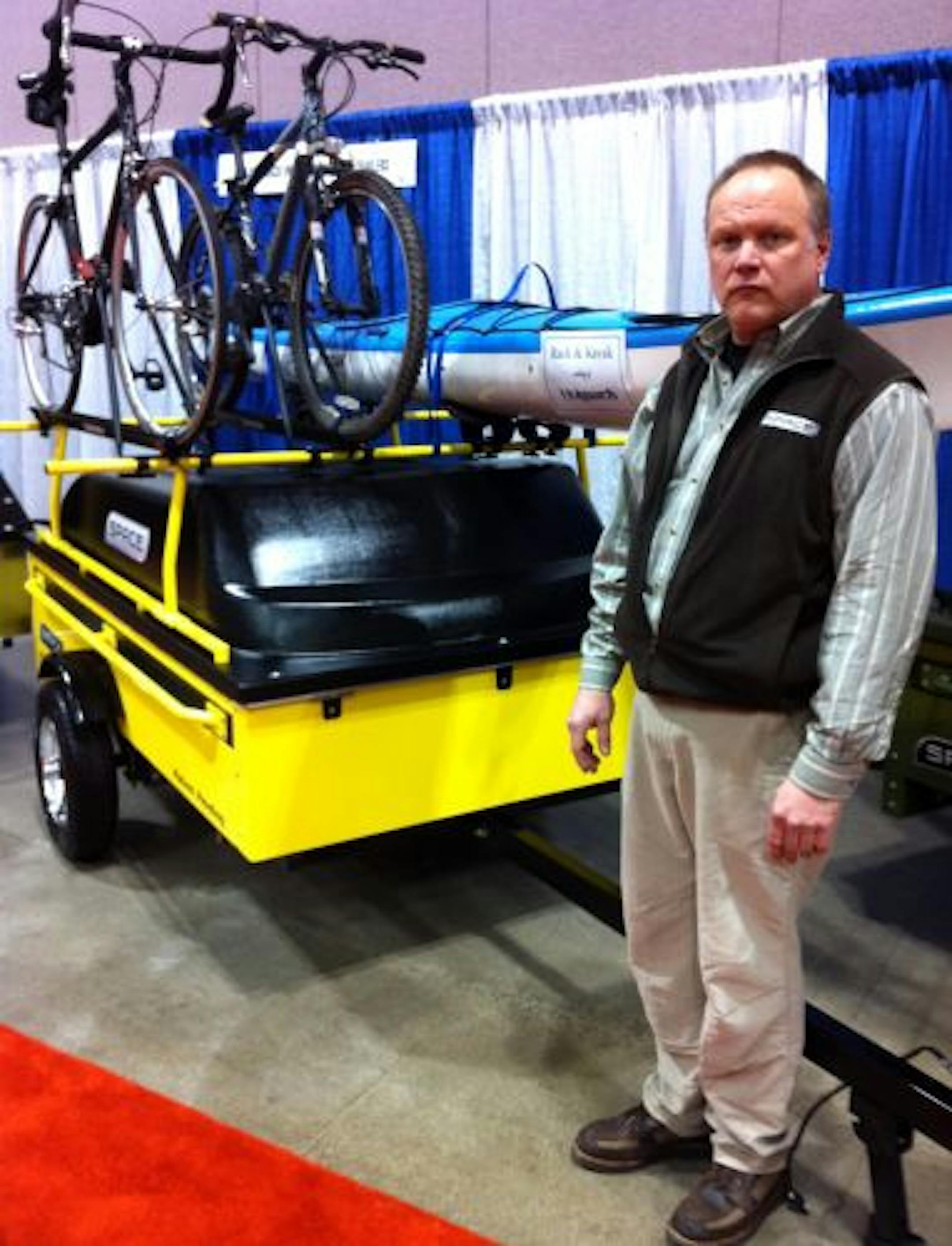 Brennan Olson of Space Trailers in Burnsville alongside one the trailers his company manufactures to carry recreational and other gear. Outfitted with a rack for bikes and a kayak, this trailer — like others Olson's company makes — offers dry storage designed to be pulled by today's smaller cars and trucks.