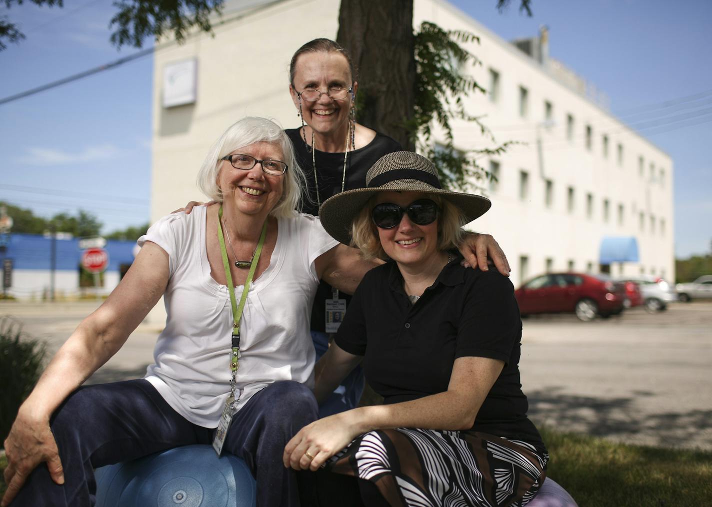 From left, nurse-midwives Anne Johnson and Rebeca Barroso and nurse Chris Weimholt are shown with the Catholic Charities building that houses Seton clinic in the background.