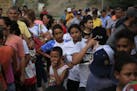 Migrants from countries including Honduras, Cuba, Venezuela, and Nicaragua, line up to receive a meal donated by volunteers from the U.S., at the foot