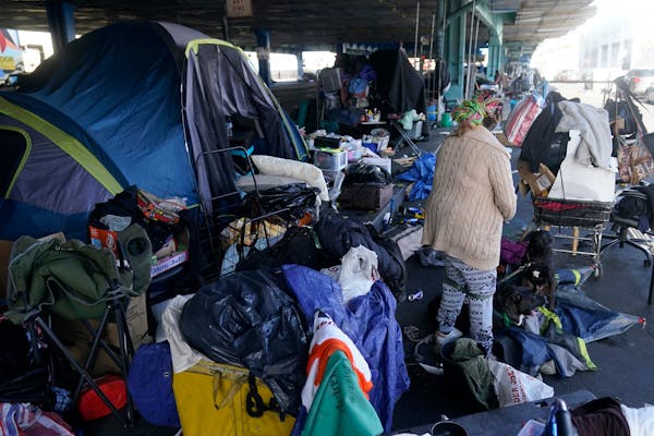 FILE - A woman gathers possessions to take before a homeless encampment was cleaned up in San Francisco, Aug. 29, 2023. The Supreme Court will hear it