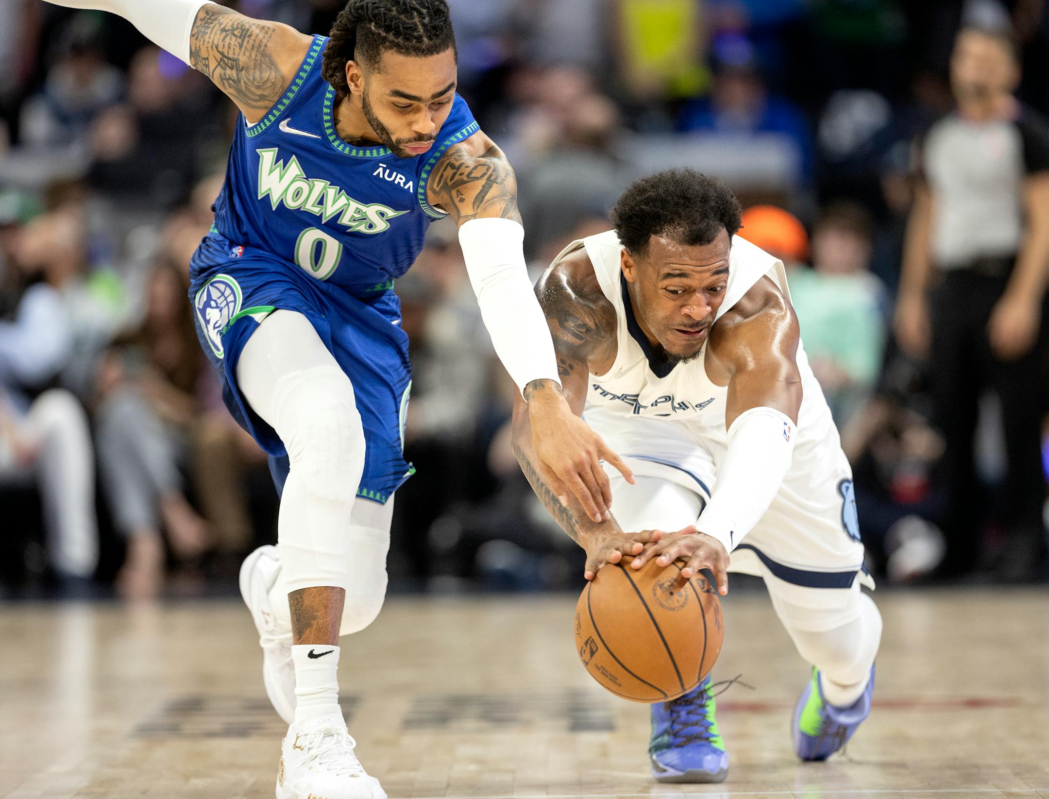 D'Angelo Russell (0) of the Minnesota Timberwolves and Xavier Tillman Jr. (2) of the Memphis Grizzlies fight for the ball in the first quarter.