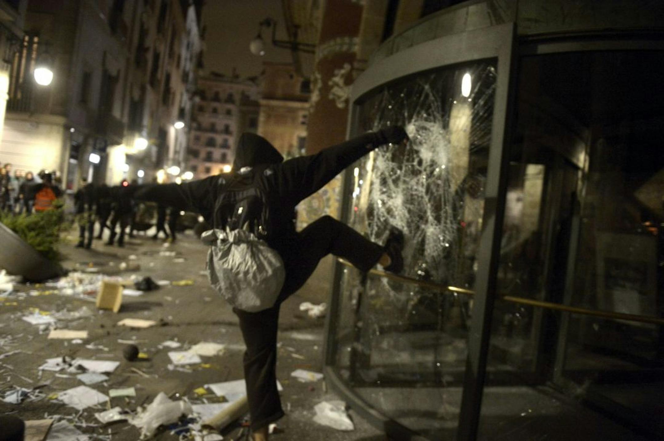 A demonstrator kicks the glass at the main entrance of "Palau de la Musica" during clashes following a demonstration during a general strike in Barcelona Spain, Wednesday, Nov. 14, 2012. Spain's main trade unions stage a general strike, coinciding with similar work stoppages in Portugal and Greece, to protest government-imposed austerity measures and labor reforms. The strike is the second in Spain this year.