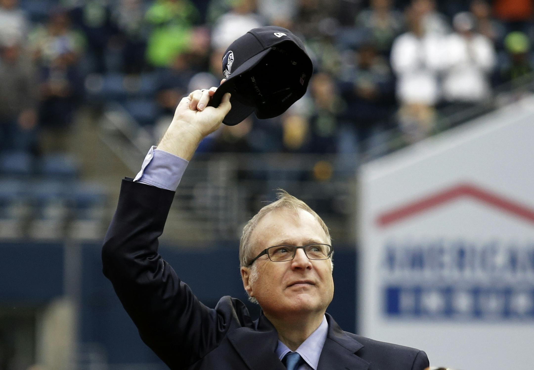 In this Sept. 17, 2017 photo, Seattle Seahawks owner Paul Allen waves as he is honored for his 20 years of team ownership before an NFL football game against the San Francisco 49ers in Seattle. Allen, who co-founded Microsoft with his childhood friend Bill Gates before becoming a billionaire philanthropist who invested in conservation, space travel, arts and culture and professional sports, died Monday. He was 65. (AP Photo/Elaine Thompson)