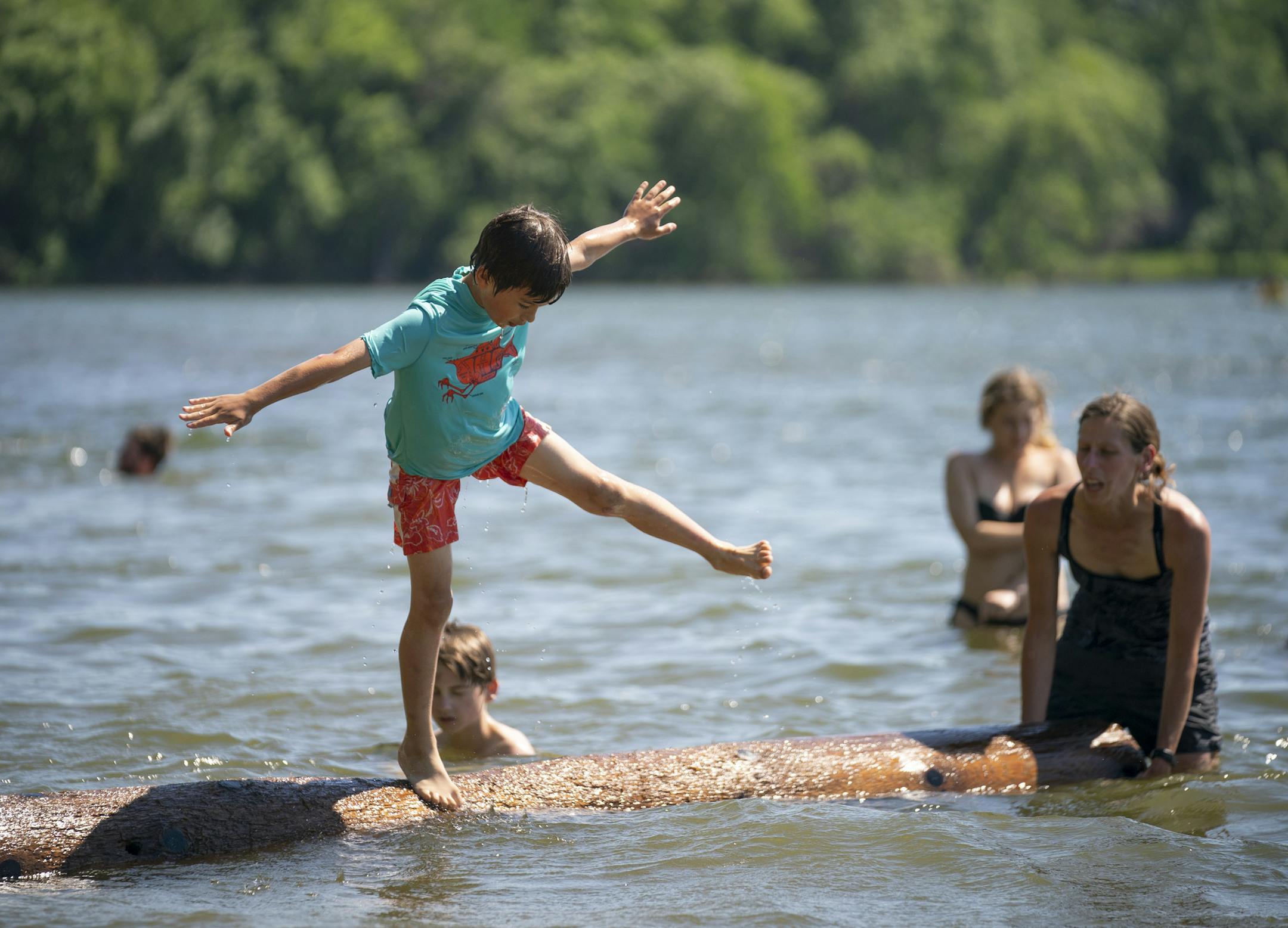 Micah Wass, 8, have fallen off a log with help from his mom, Amy, who was turning it at the end Monday afternoon. ] JEFF WHEELER • Jeff.Wheeler@startribune.com The Twin Cities experienced full on summer weather Monday, June 8, 2020 sending families to the beaches to cool off. At Cedar Lake East Beach it was lively, but not overcrowded and the breeze was strong.