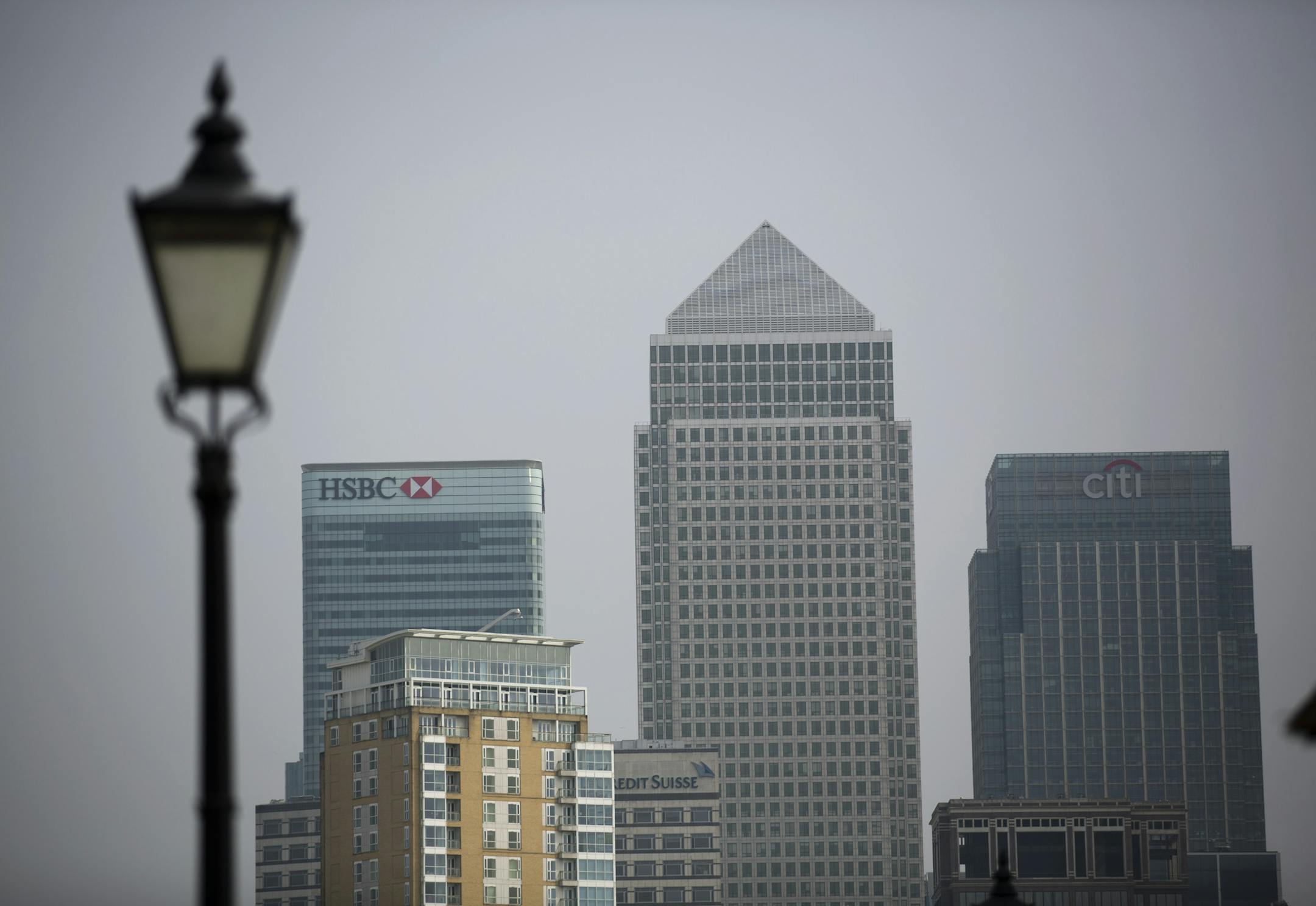 A Victorian era styled street lamp stands in the foreground as an exterior views shows the global headquarters building of HSBC, at left, next to the pyramid roof topped building "One Canada Square" and the Citigroup Centre building, right, in the Canary Wharf business district of London, Friday, April 24, 2015. HSBC is considering moving its headquarters from Britain in the wake of "regulatory and structural reforms" imposed after the 2008 financial crisis, the bank's chairman said Friday. (AP
