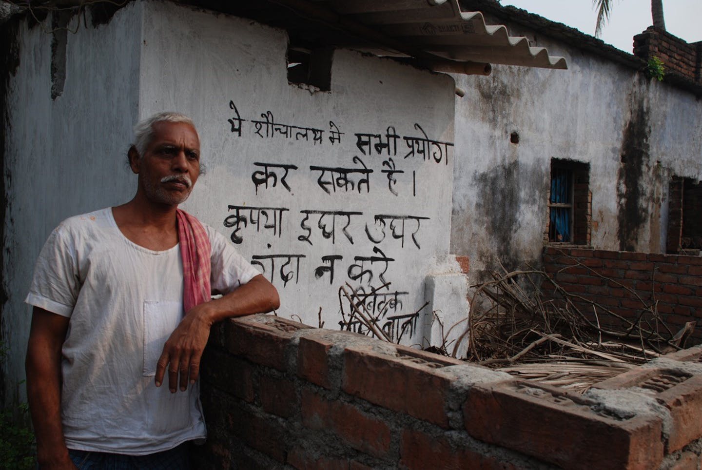 Man dubbed Mr. Toilet Man for building a place for his villagers in Sakri Gali. Mr Toilet Man outside his house with sign saying toilet open to public.