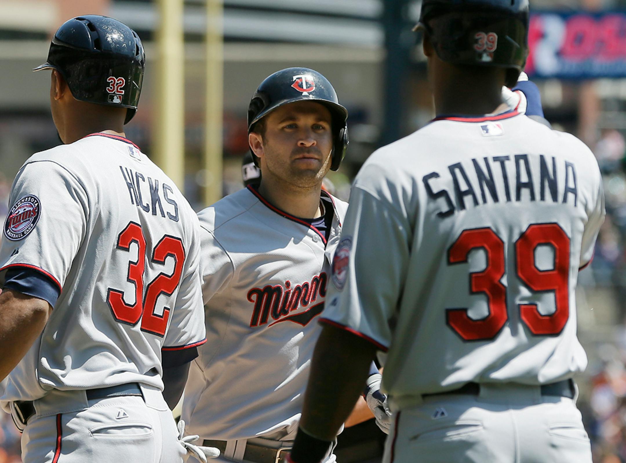 Minnesota Twins' Brian Dozier, center, is greeted by teammates Aaron Hicks (32) and Danny Santana (39) after they scored on Dozier's three-run home run during the third inning of a baseball game against the Detroit Tigers in Detroit, Saturday, May 10, 2014. (AP Photo/Carlos Osorio)