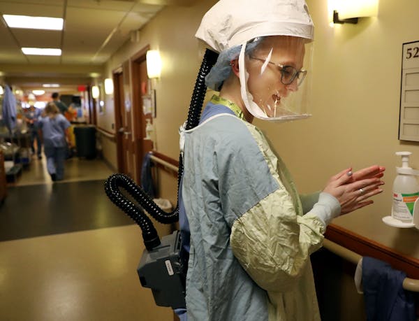 After donning personal protective equipment RN Sarah Neva sanitizes her hands before going in to check on a COVID-19 patient on the fifth floor at Bet