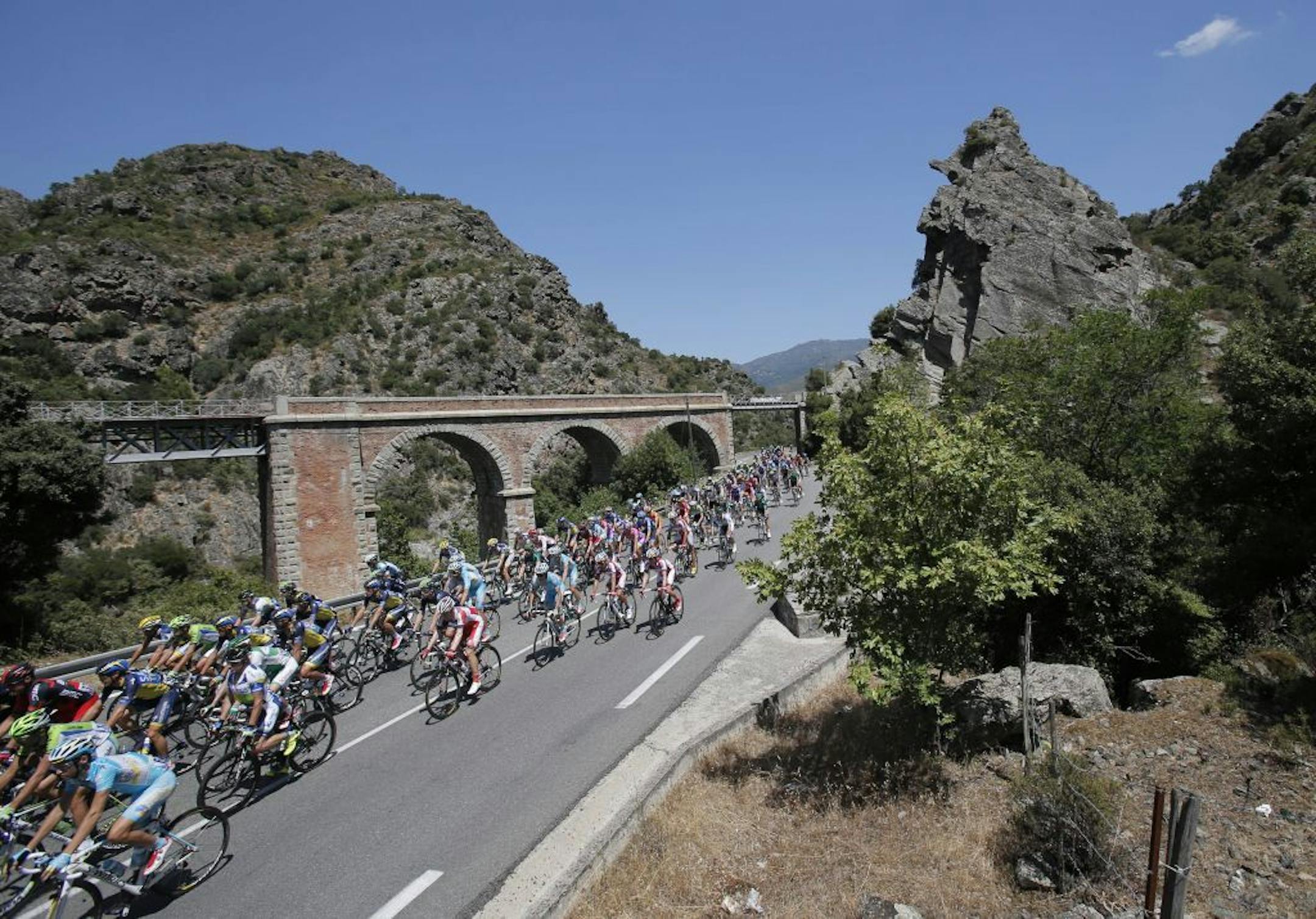 The pack passes a railroad bridge near Ponte Leccia during the second stage of the Tour de France cycling race over 156 kilometers (97.5 miles) with start in Bastia and finish in Ajaccio, Corsica island, France, Sunday June 30, 2013.