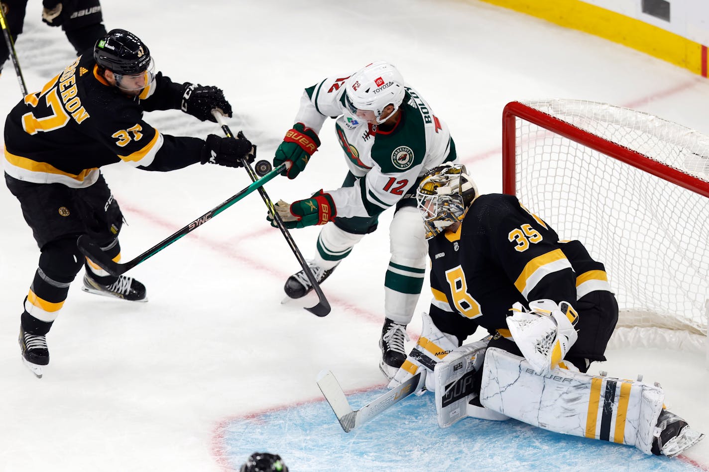 Boston Bruins' Patrice Bergeron (37) battles Minnesota Wild's Matt Boldy (12) for the puck during the second period of an NHL hockey game, Saturday, Oct. 22, 2022, in Boston. (AP Photo/Michael Dwyer)