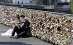 FILE - This Wednesday April 16, 2014 file photo shows a newly wed couple resting on the Pont des Arts in Paris, France. Any hope that the love locks t