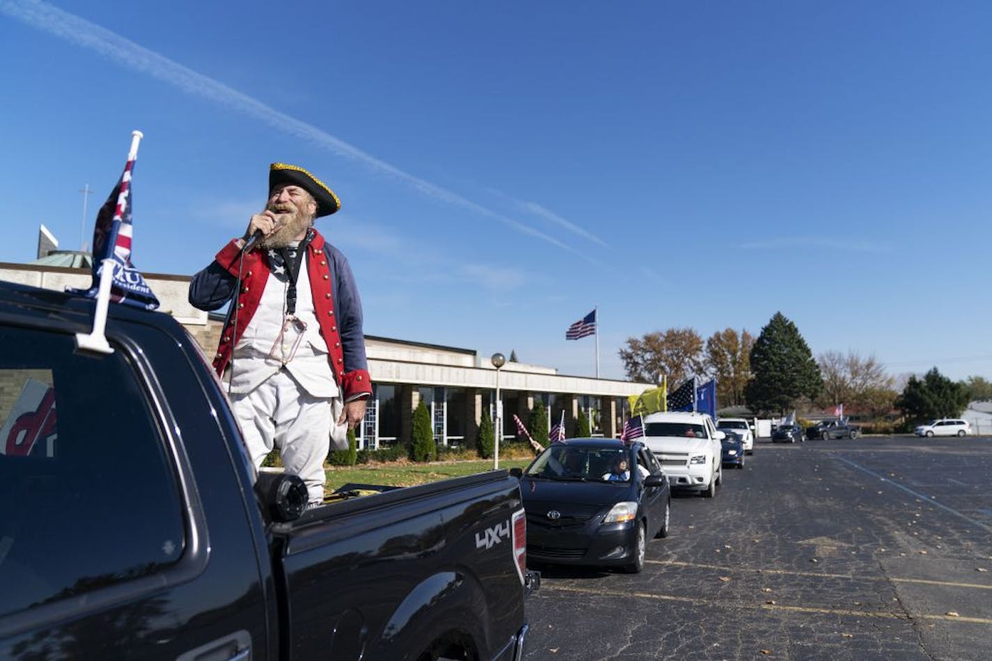 Trump supporter Matthew Woods, dressed as a Continental Army soldier, leads a Trump Train Rally through the parking lot of a polling precinct on Election Day in Warren, Mich., Tuesday, Nov. 3, 2020.