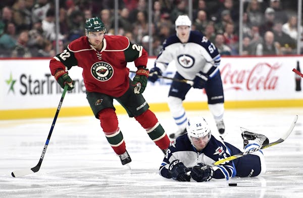Winnipeg Jets center Marko Dano chased the puck down to the ice while being challenged from behind by Minnesota Wild right wing Nino Niederreiter.