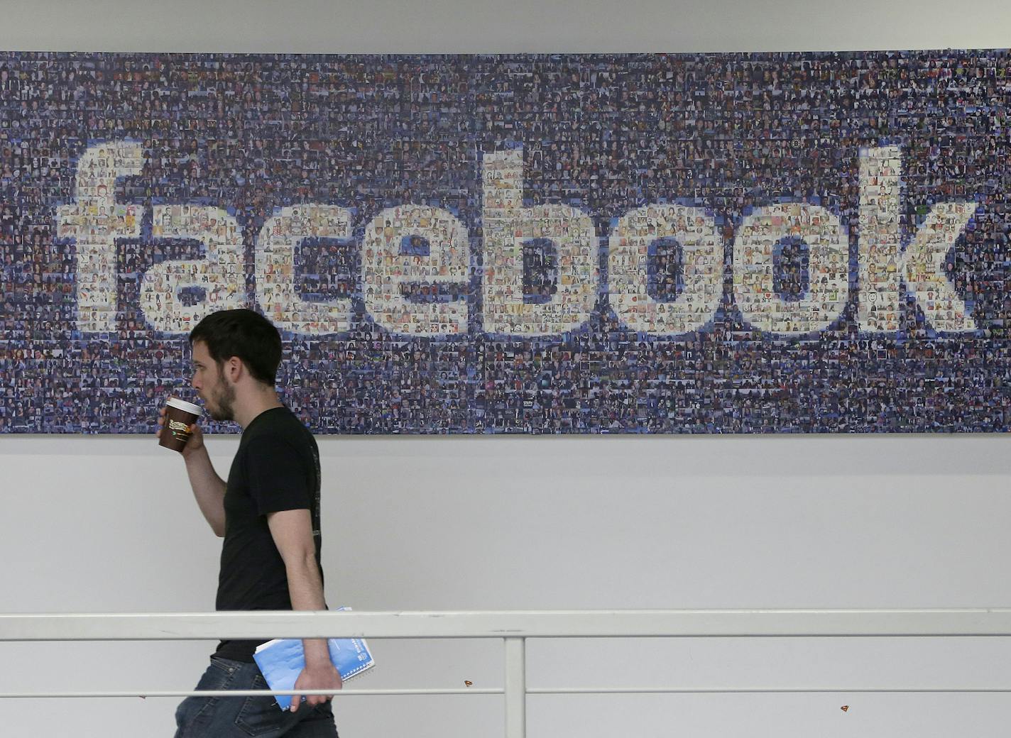 A Facebook employee walks past a sign at Facebook headquarters in Menlo Park, Calif., Friday, March 15, 2013. Companies say extraordinary campuses are a necessity, to recruit and retain top talent, and to spark innovation and creativity in the workplace. And there are business benefits and financial results for companies that keep their workers happy. (AP Photo/Jeff Chiu) ORG XMIT: MIN2013050117204305 ORG XMIT: MIN1305011723443112