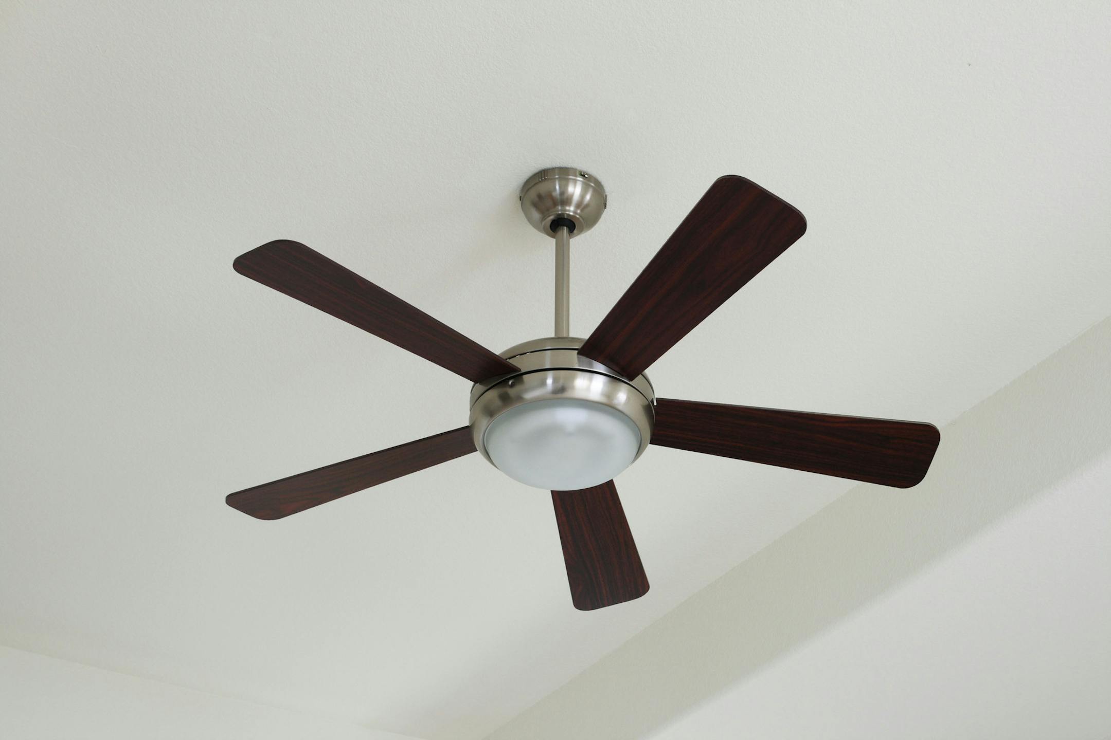 Silver and wood ceiling fan with a light on a white ceiling. (Dreamstime/TNS) ORG XMIT: 1197156