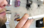 FILE - A sales associate demonstrates the use of a electronic cigarette and the smoke like vapor that comes from it in Aurora, Colo. on Wednesday, Mar