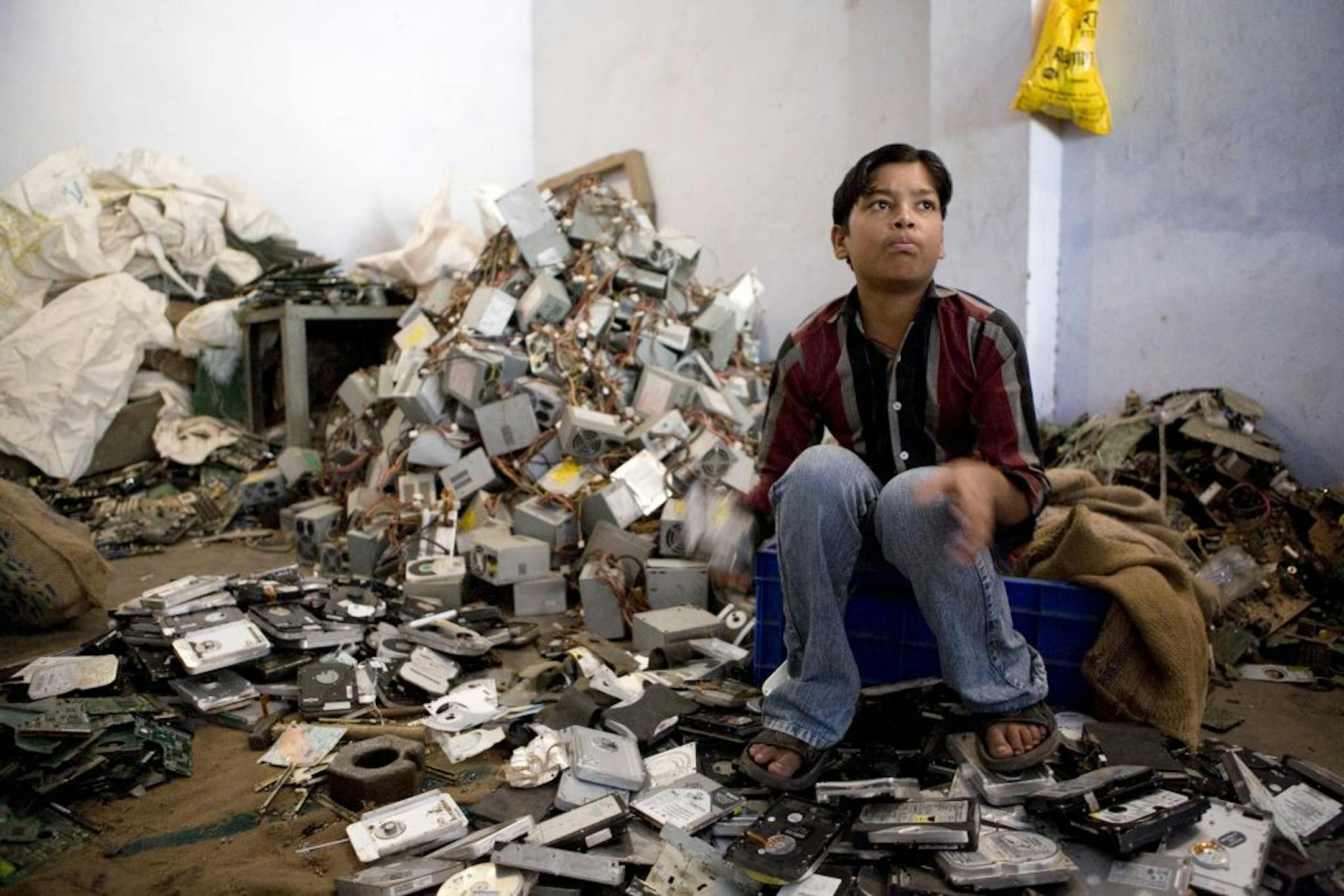 A young boy separates various parts of discarded computers in a recycling garage in New Delhi, India, on Wednesday, July 11, 2007. Electronic waste recycling services have been growing in parallel with the use of electronic products. Photographer: Sanjit Das/Bloomberg News