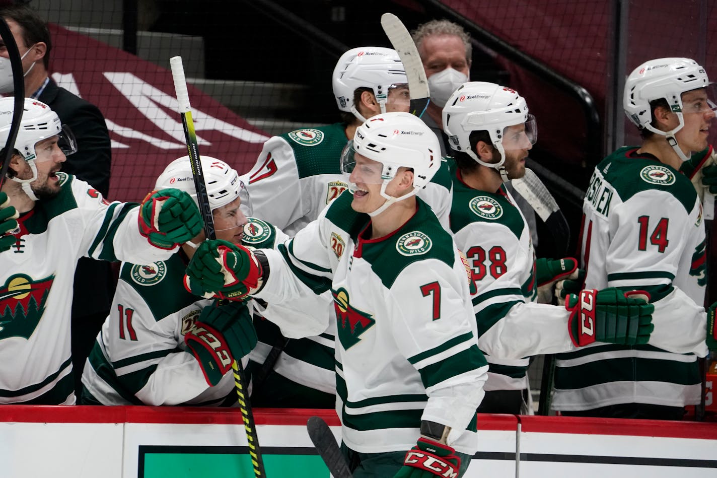 Minnesota Wild center Nico Sturm, front, is congratulated as he passes the team box after scoring a goal against the Colorado Avalanche during the third period of an NHL hockey game Wednesday, Feb. 24, 2021, in Denver. (AP Photo/David Zalubowski)