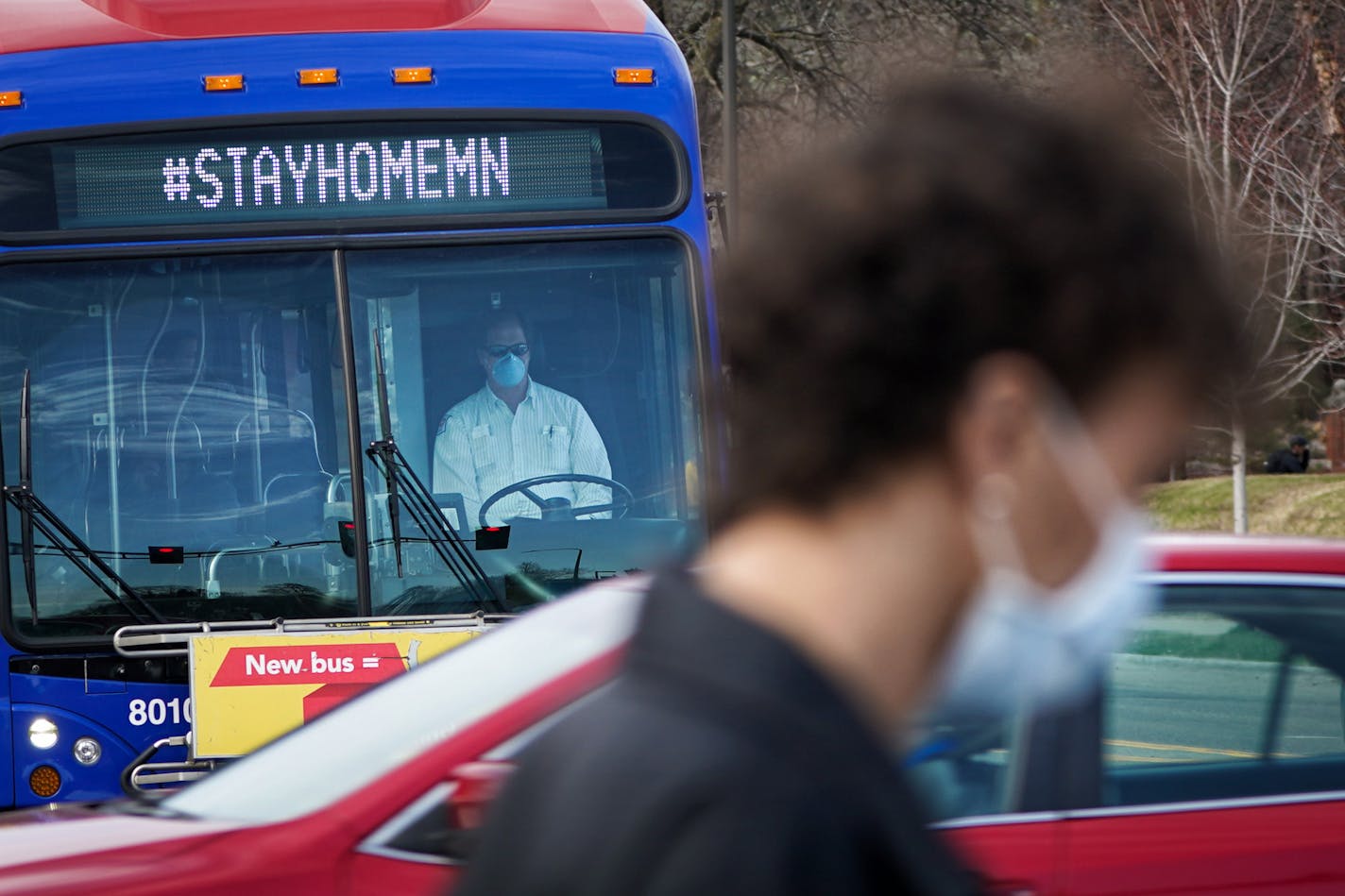 A masked Metro Transit driver ran his route along Snelling Avenue and a masked pedestrian walked along Grand Ave in St Paul Sunday afternoon. [GLEN STUBBE • glen.stubbe@startribune.com]