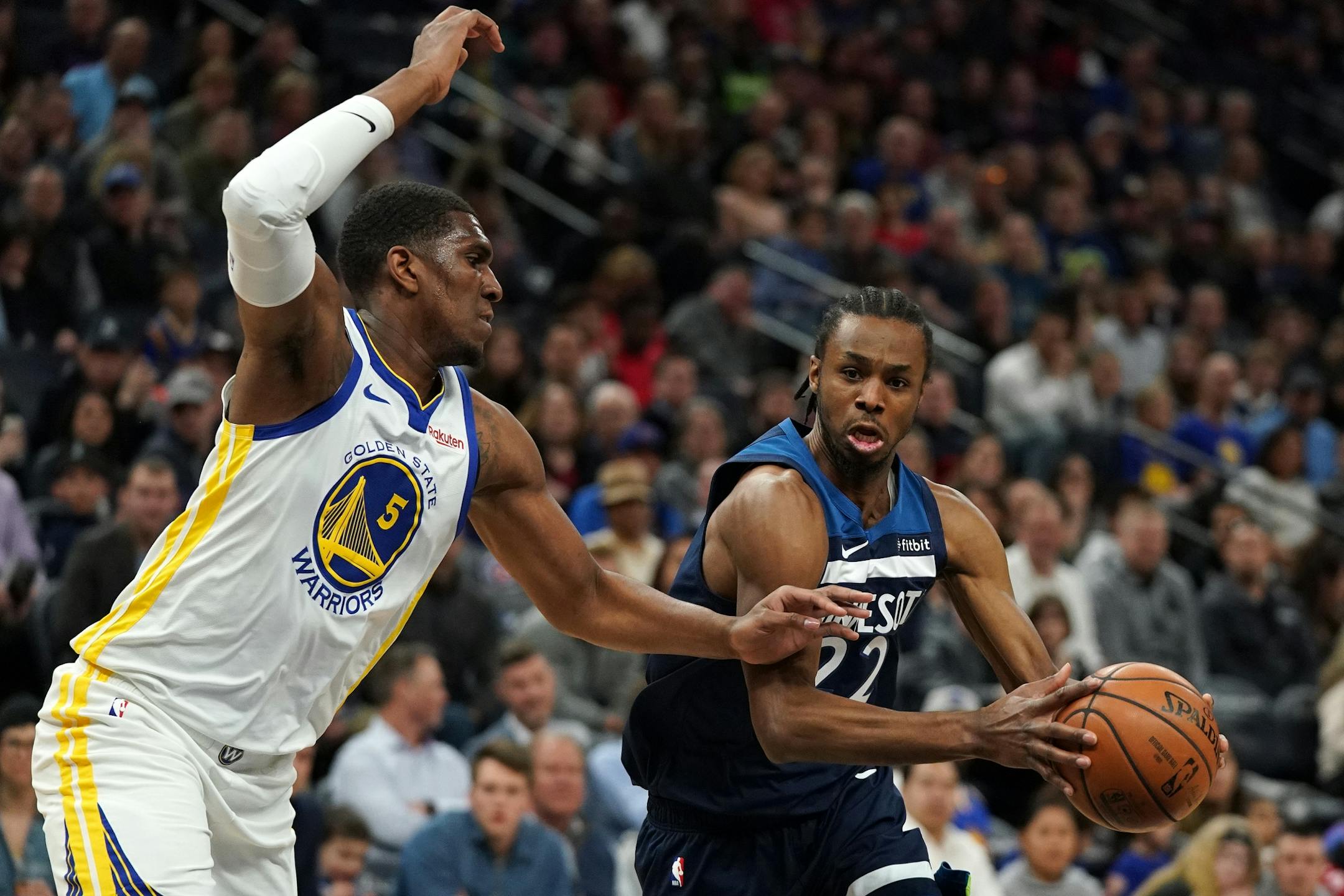 Minnesota Timberwolves forward Andrew Wiggins (22) looked to take the ball around Golden State Warriors center Kevon Looney (5) in the first half.