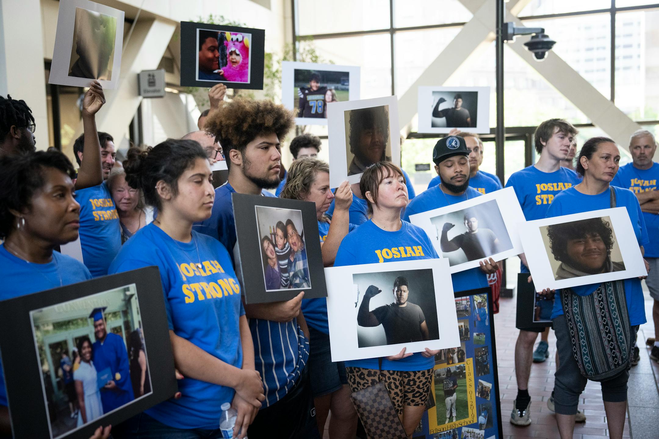 Family and friends stand with the family of Josiah Oakley holding pictures of him after the sentencing for Sylvester Vaughn.