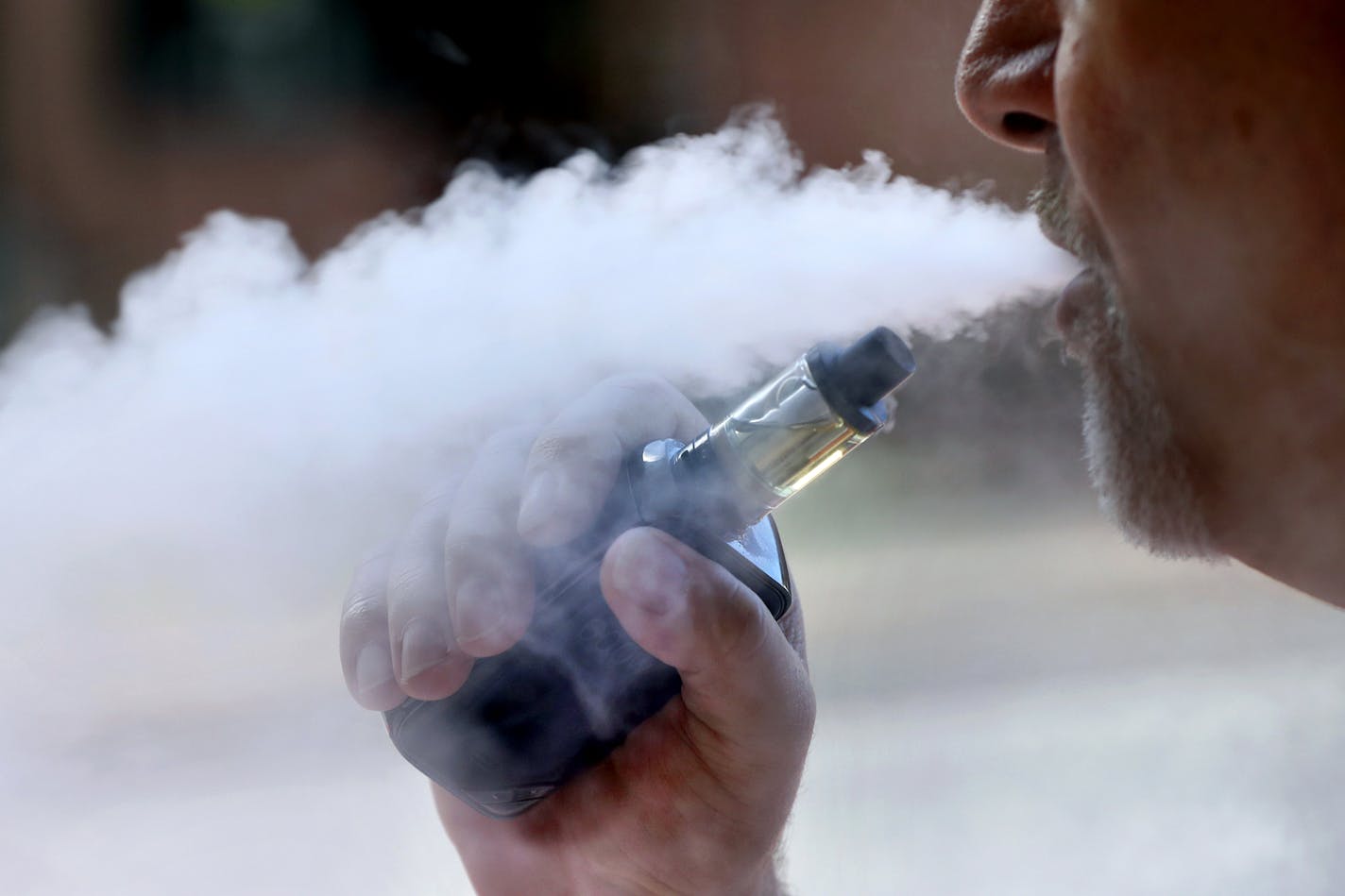 In this Aug. 28, 2019, file photo, a man exhales while smoking an e-cigarette in Portland, Maine.