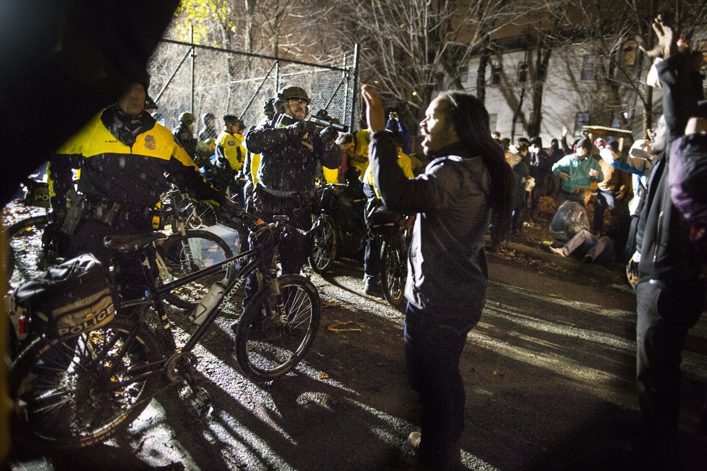 In this Wednesday, Nov. 18, 2015 photo, Jeremiah Ellison, center right, son of U.S. Rep. Keith Ellison, stands near police during a protest at the Minneapolis Police Department 4th Precinct building in Minneapolis.