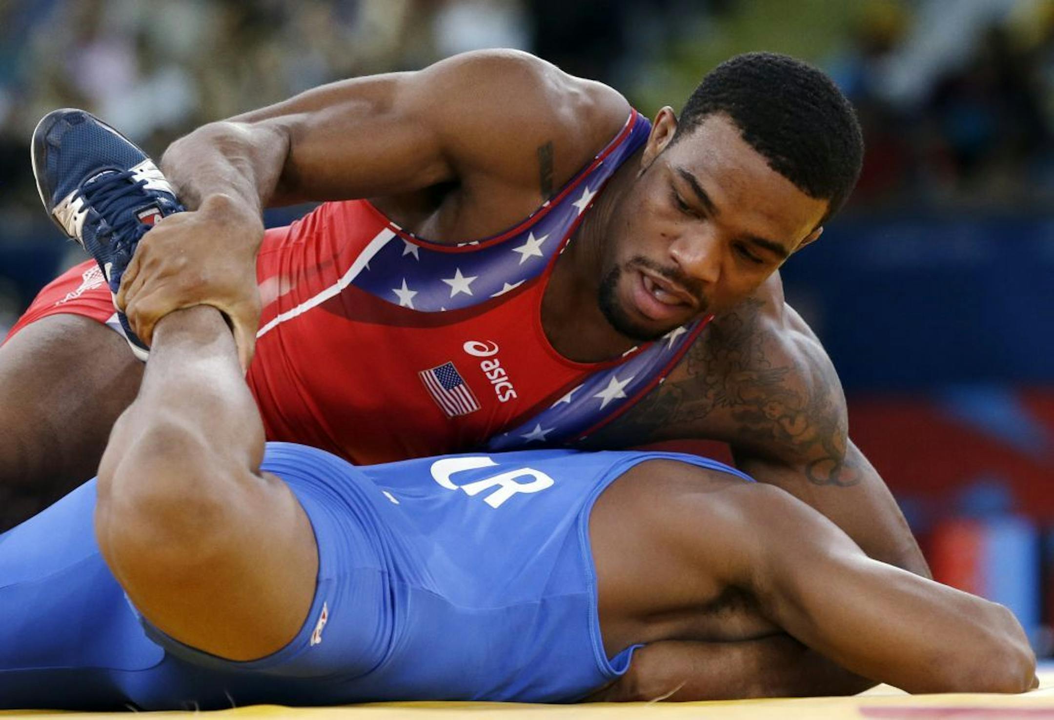 United States' Jordan Ernest Burroughs, in red, and Puerto Rico's Francisco Daniel Soler Tanco, in blue, compete during a 74-kg men's freestyle wrestling competition at the 2012 Summer Olympics in London.