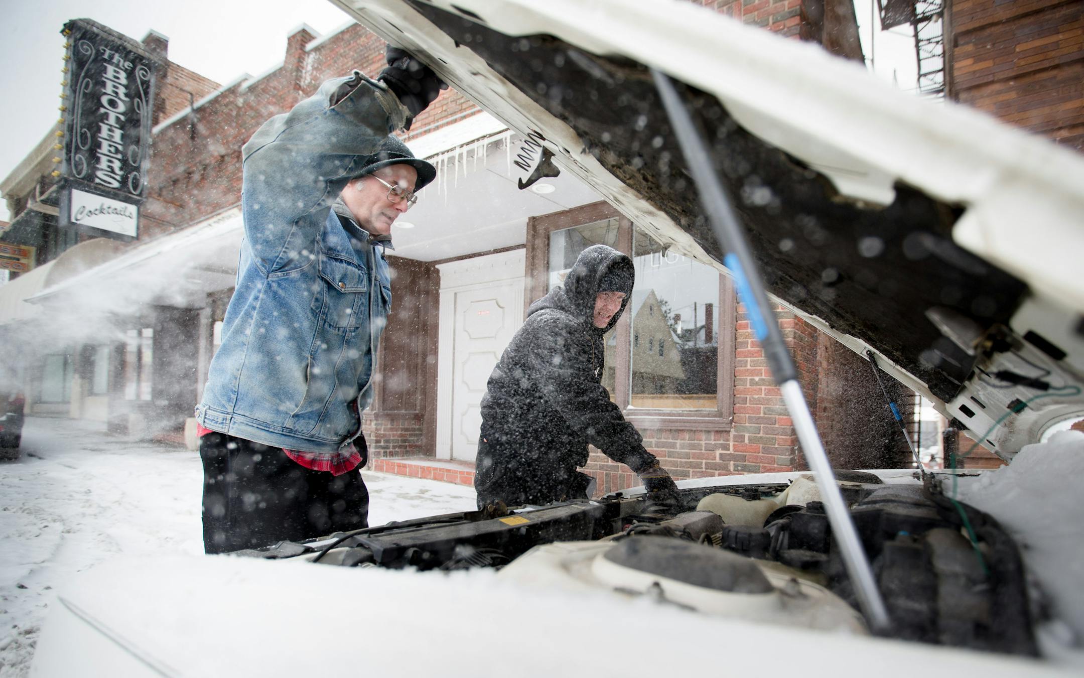 In this Jan. 5, 2015 photo, Russell Petersen, left, watches as Tony Olson, prepares to jump start Petersen's 1989 Oldsmobile Delta 88 in Omaha Neb. A winter storm system moving through the Midwest is expected to bring snow and cold temperatures to parts of Nebraska and Iowa. (AP Photo/The World-Herald, Kent Sievers) MAGS OUT; ALL NEBRASKA LOCAL BROADCAST TELEVISION OUT