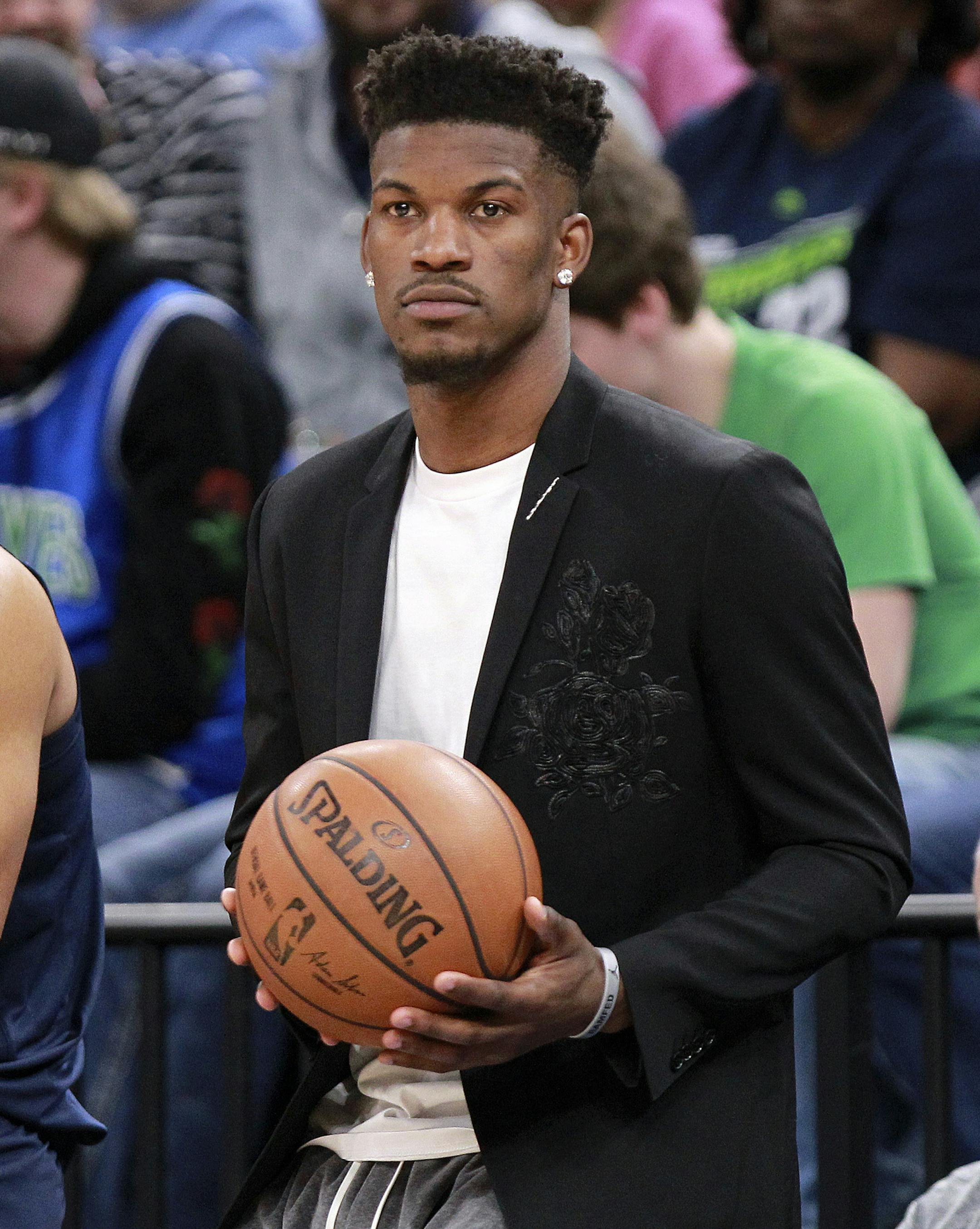 Injured Minnesota Timberwolves guard Jimmy Butler holds the game ball during a time out against the Houston Rockets in the third quarter of an NBA basketball game Sunday, March 18, 2018, in Minneapolis. (AP Photo/Andy Clayton-King)