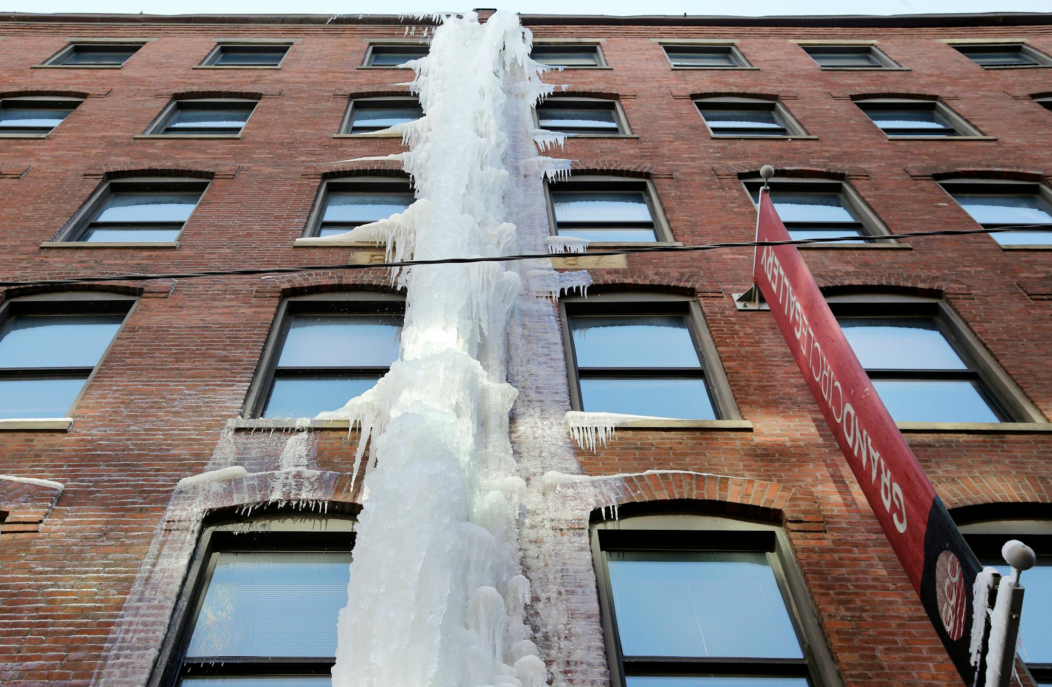 A cascade of ice adheres along the side of a brick building in downtown Boston, Friday, Feb. 20, 2015. Ice dams are a growing concern for homeowners in snowbound New England, where another storm is expected to bring snow, rain and freezing rain this weekend. The formations develop at the edge of a building's roof and prevent melting snow from draining, causing interior leaks and other damage. (AP Photo/Elise Amendola)