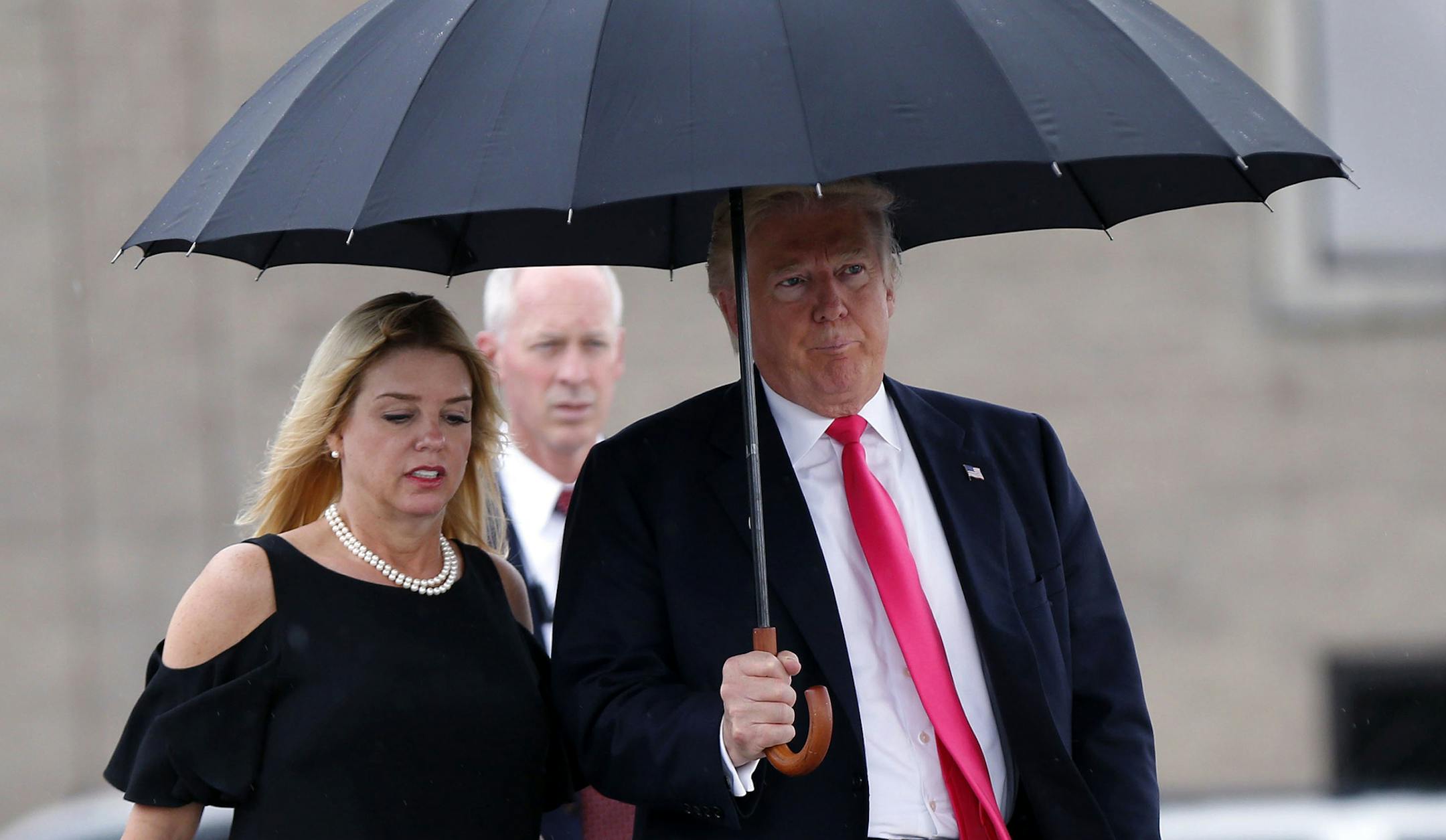 FILE - In this Aug. 24, 2016 file photo, Republican presidential candidate Donald Trump walks in the rain with Florida Attorney General Pam Bondi as they arrive at a campaign rally in Tampa, Fla. House Democrats are calling for a federal criminal investigation into an improper $25,000 donation Trump's charity made to a political group supporting Florida's attorney general after her office said it was weighing legal action against Trump University. In a letter that all 16 Democrats on the House J