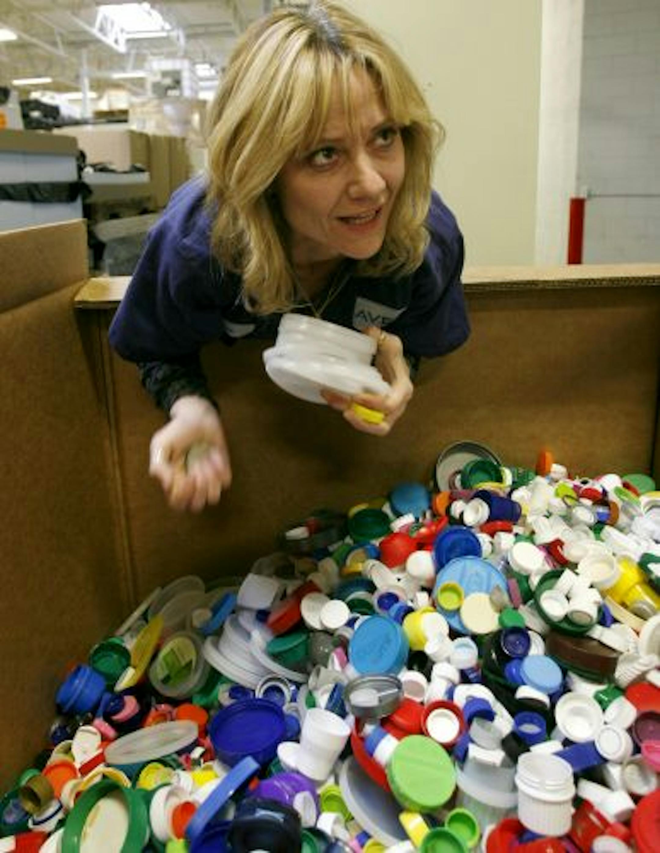 Aveda employee Lori Pasch sorts through bottle caps and other plastic brought in for recycling for plastic not suitable for recycling in the special caps program.