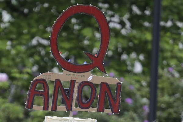 FILE - In this May 14, 2020 file photo, a person carries a sign supporting QAnon at a protest rally in Olympia, Wash. Walmart, Amazon and other corpor
