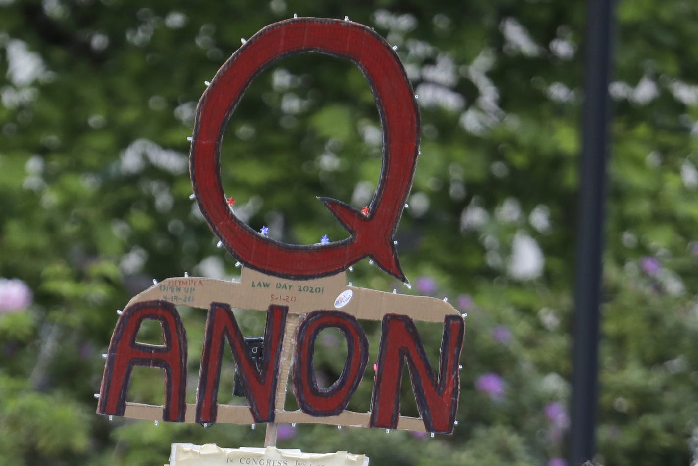 FILE - In this May 14, 2020 file photo, a person carries a sign supporting QAnon at a protest rally in Olympia, Wash. Walmart, Amazon and other corporate giants donated money to a Tennessee state lawmaker's re-election campaign after she used social media to amplify and promote the QAnon conspiracy theory. That's according to an Associated Press review of campaign finance records and online posts by Republican state Rep. Susan Lynn. (AP Photo/Ted S. Warren, File)