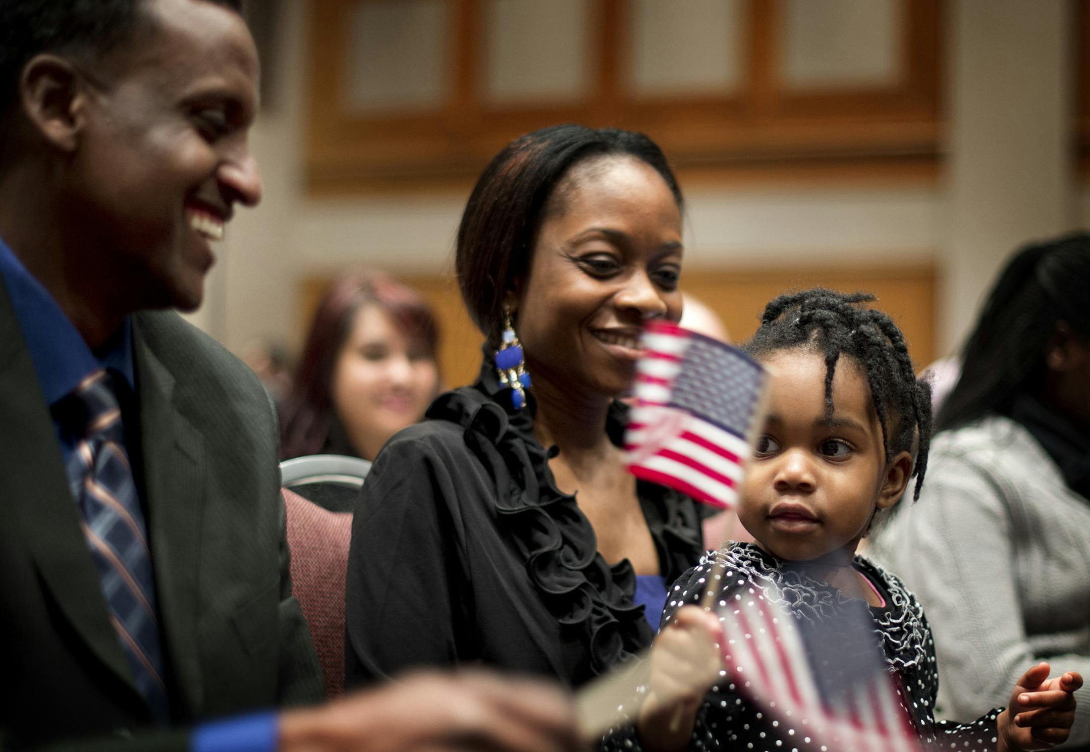 Mohamed Adam from Somalia made friends with Alfreanna Reeves, 2 as they waved flags to John Philip Sousa's Stars and Stripes Forever. Holding Alfreanna is her mom Alfrie Reeves. Approximately 1,300 immigrants from 99 different countries were sworn in as new U.S. citizens Thursday morning during a naturalization ceremony at the Minneapolis Convention Center, Thursday, January 24, 2013. ] GLEN STUBBE * gstubbe@startribune.com ORG XMIT: MIN1301241331330225