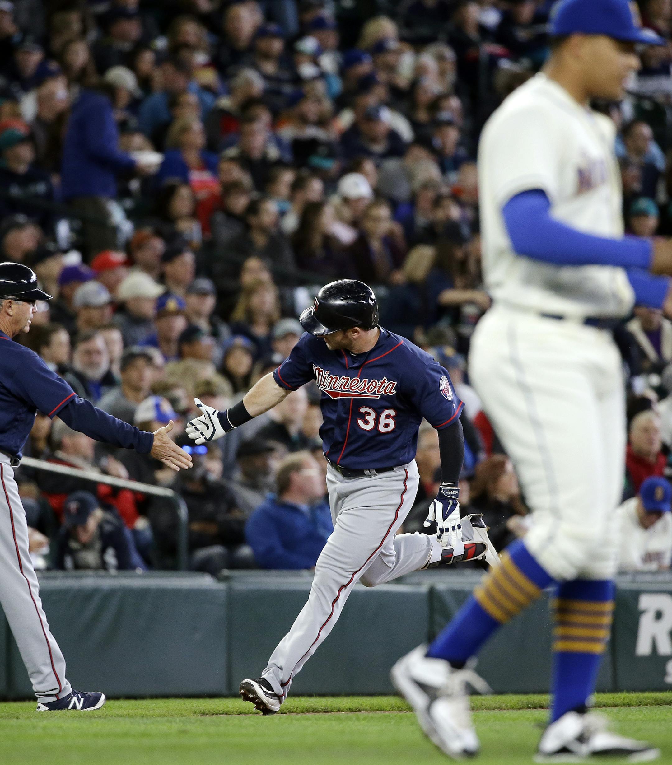 Seattle Mariners starting pitcher Taijuan Walker, right, returns to the mound as Minnesota Twins' Robbie Grossman (36) is congratulated by third base coach Gene Glynn on Grossman's home run in the second inning of a baseball game Sunday, May 29, 2016, in Seattle. (AP Photo/Elaine Thompson)