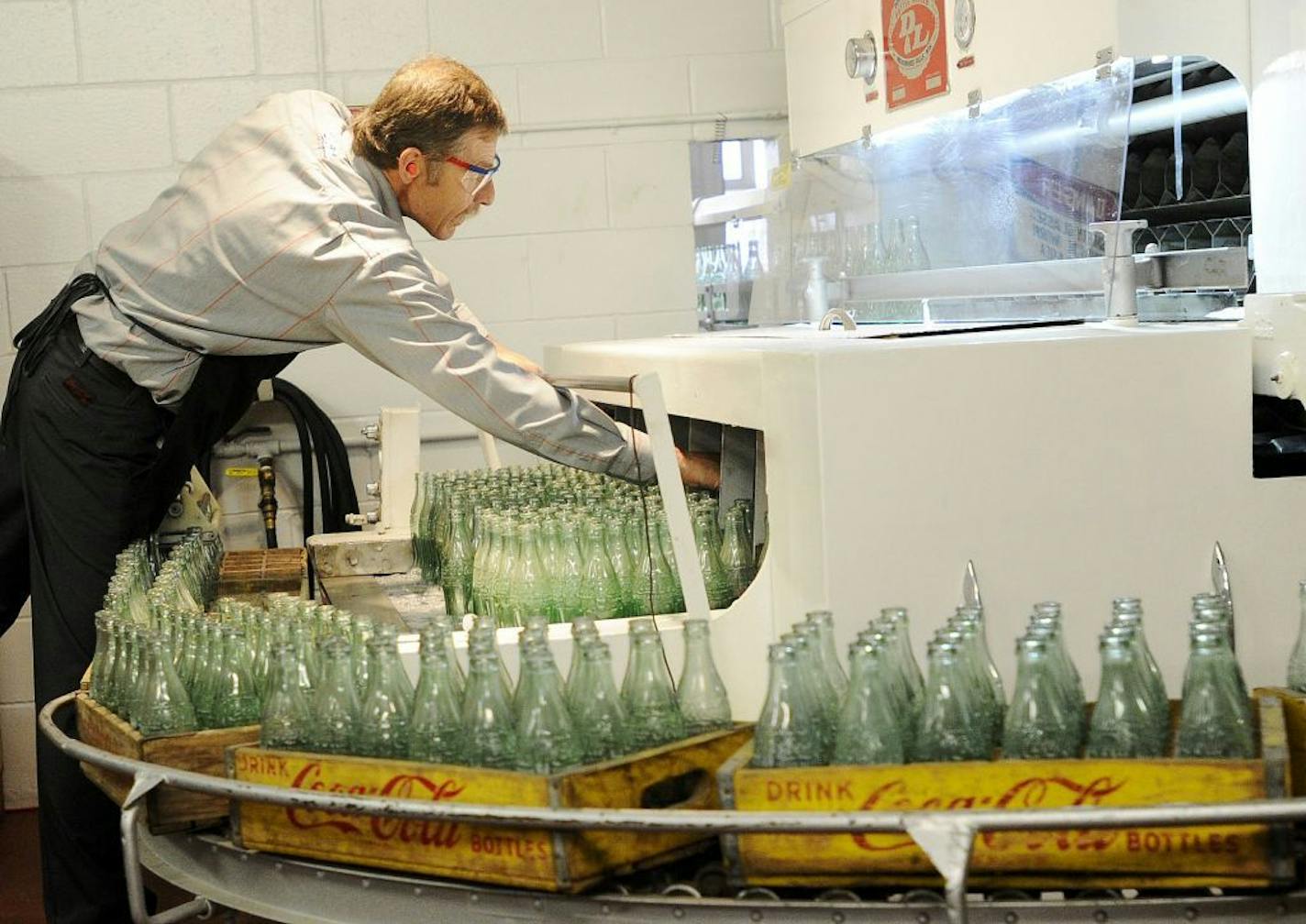 FILE - In this Tuesday, Oct. 9, 2012, photo, Darvin Peterson loads glass bottles into a washer before they are filled up for the last time at the Coca-Cola Bottling Company in Winona, Minn. Nearly 6,000 6.5-ounce returnable glass bottles were filled for the last time after 80 years of production.