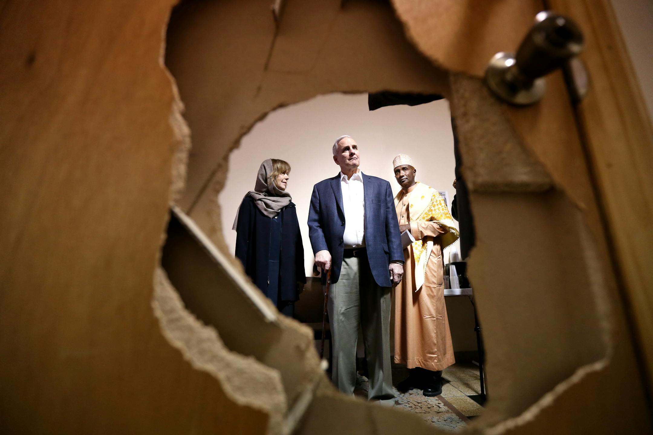 Lt. Gov. Tina Smith, Gov. Mark Dayton and Imam Ahmed Sheikomar Ibrahim looked at a door that was damaged when some one broke into and burglarized Umatul Islam Center last Wednesday.