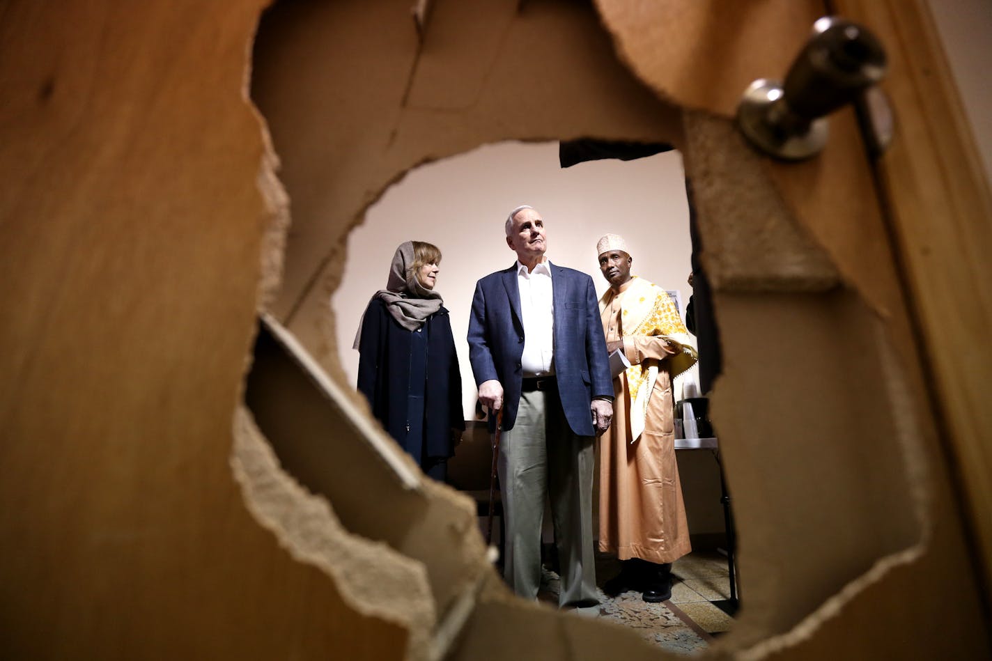 Lt. Gov. Tina Smith, Gov. Mark Dayton and Imam Ahmed Sheikomar Ibrahim looked at a door that was damaged when some one broke into and burglarized Umatul Islam Center last Wednesday.