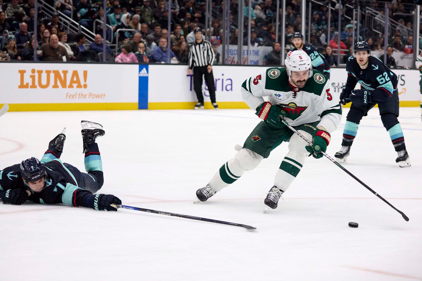 Minnesota Wild defenseman Jake Middleton (5) skates to the puck with Seattle Kraken right wing Jordan Eberle (7) reaching from the ice during the second period of an NHL hockey game, Sunday, Dec. 10, 2023, in Seattle. (AP Photo/John Froschauer)