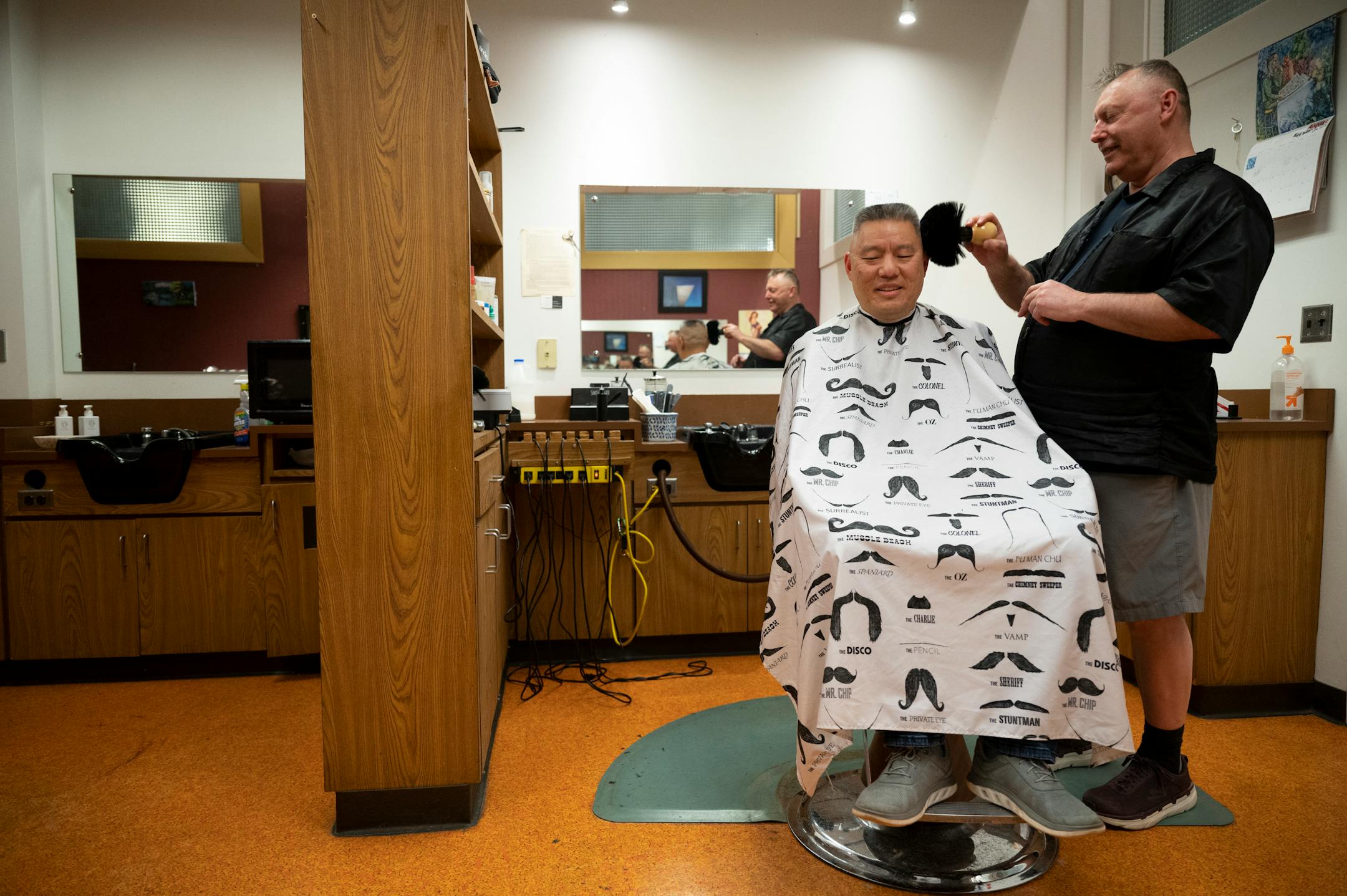 Bob Haddow uses a powder brush while giving a haircut to longtime client Alan King, a civil litigation and criminal defense attorney.