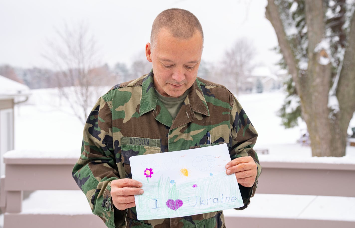 Howie Dotson poses for a portrait with drawings from Syrian and Ukrainian kids Wednesday, Nov. 16, 2022 at his childhood home in Maple Grove, Minn. Dotson performs guided art therapy with kids to help them process their trauma. ]