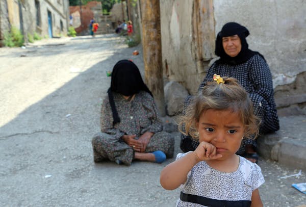 Syrian refugees sit in front of a derelict building in Haci Bayram neighborhood in Ankara, Turkey, Monday, July 27, 2015. The number of Syrian refugee